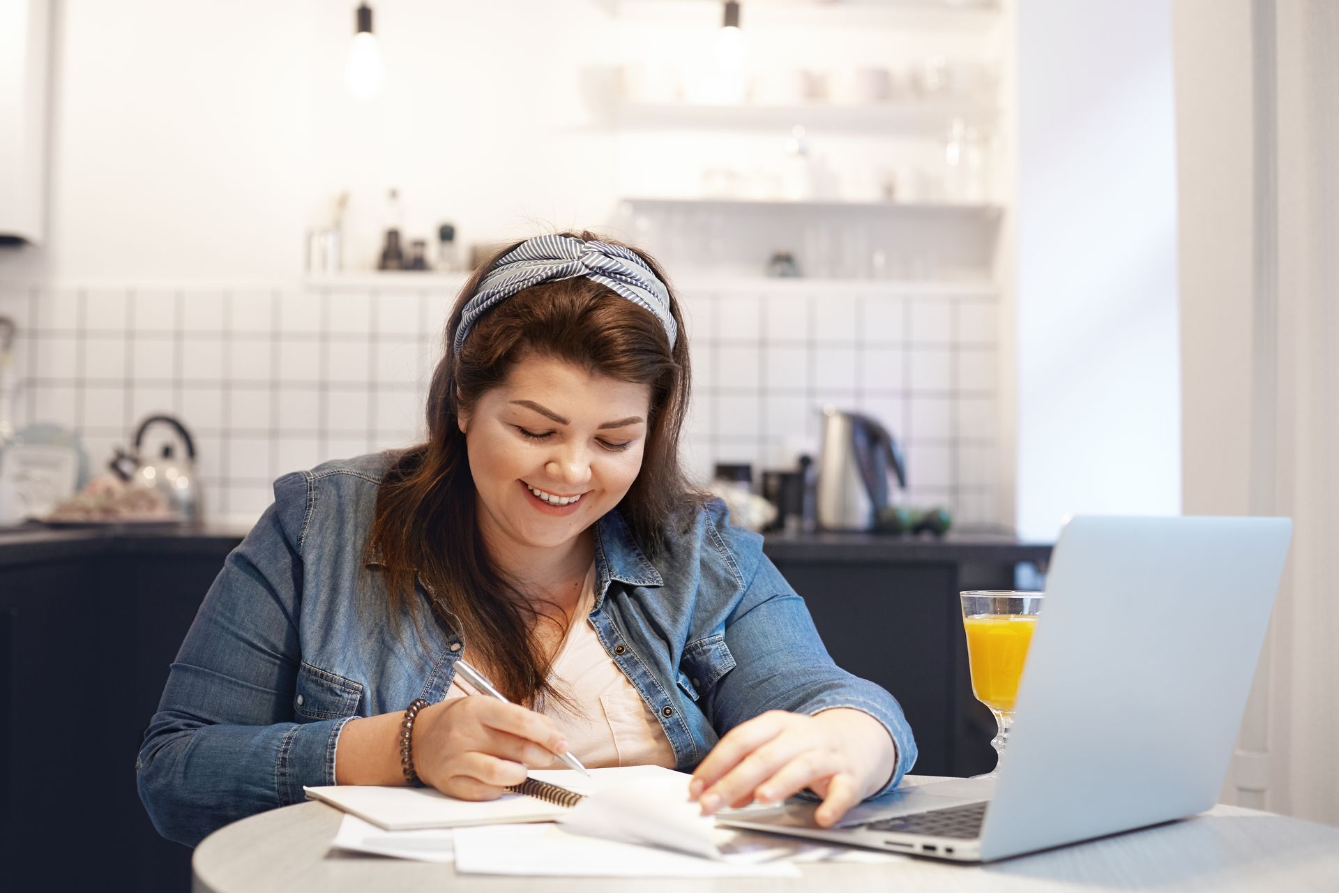 A woman is sitting at a table in front of a laptop computer.