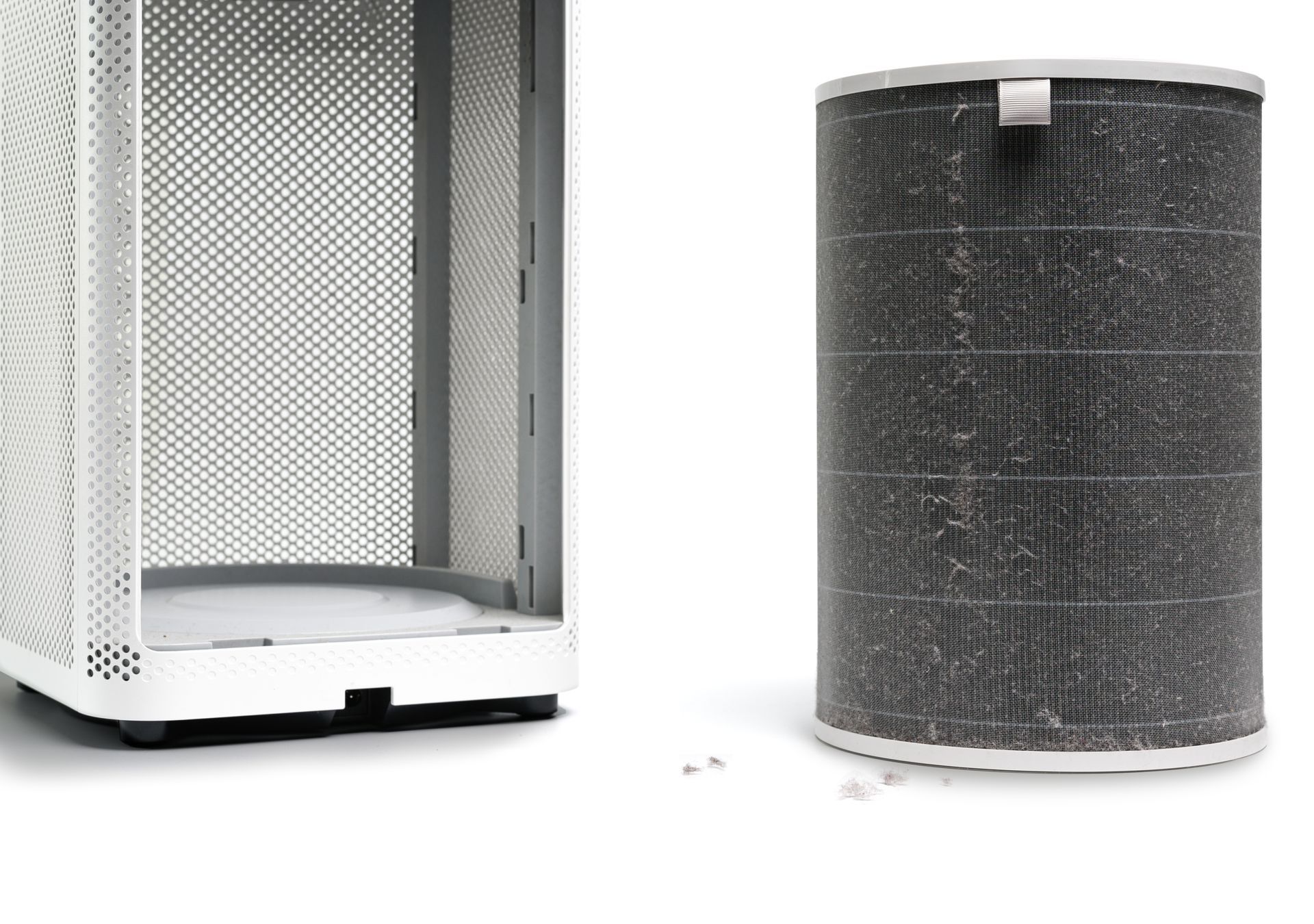A white air purifier with a dirty filter next to it.