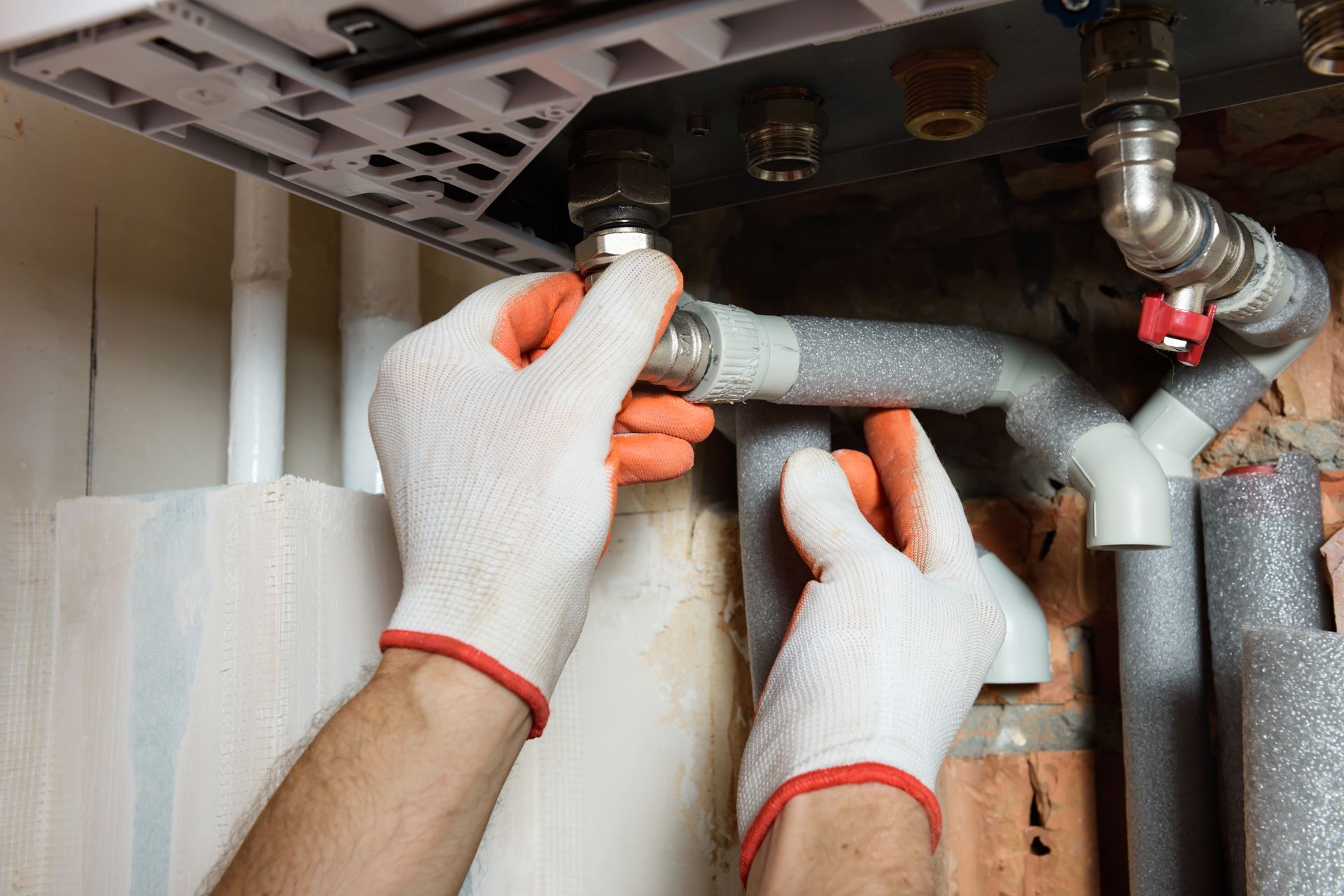 A plumber is fixing a pipe with a wrench.