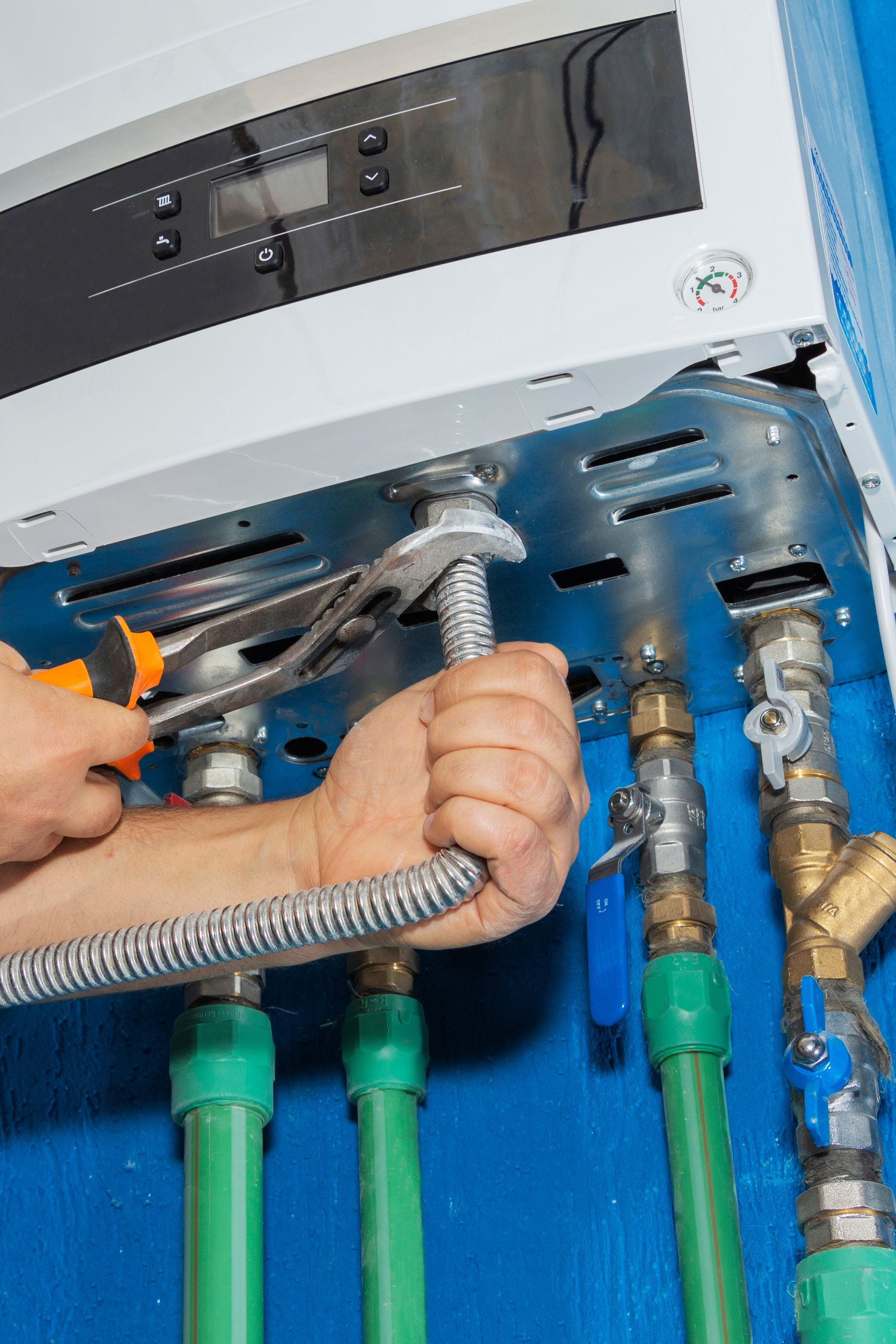 A person is fixing a water heater with a wrench.