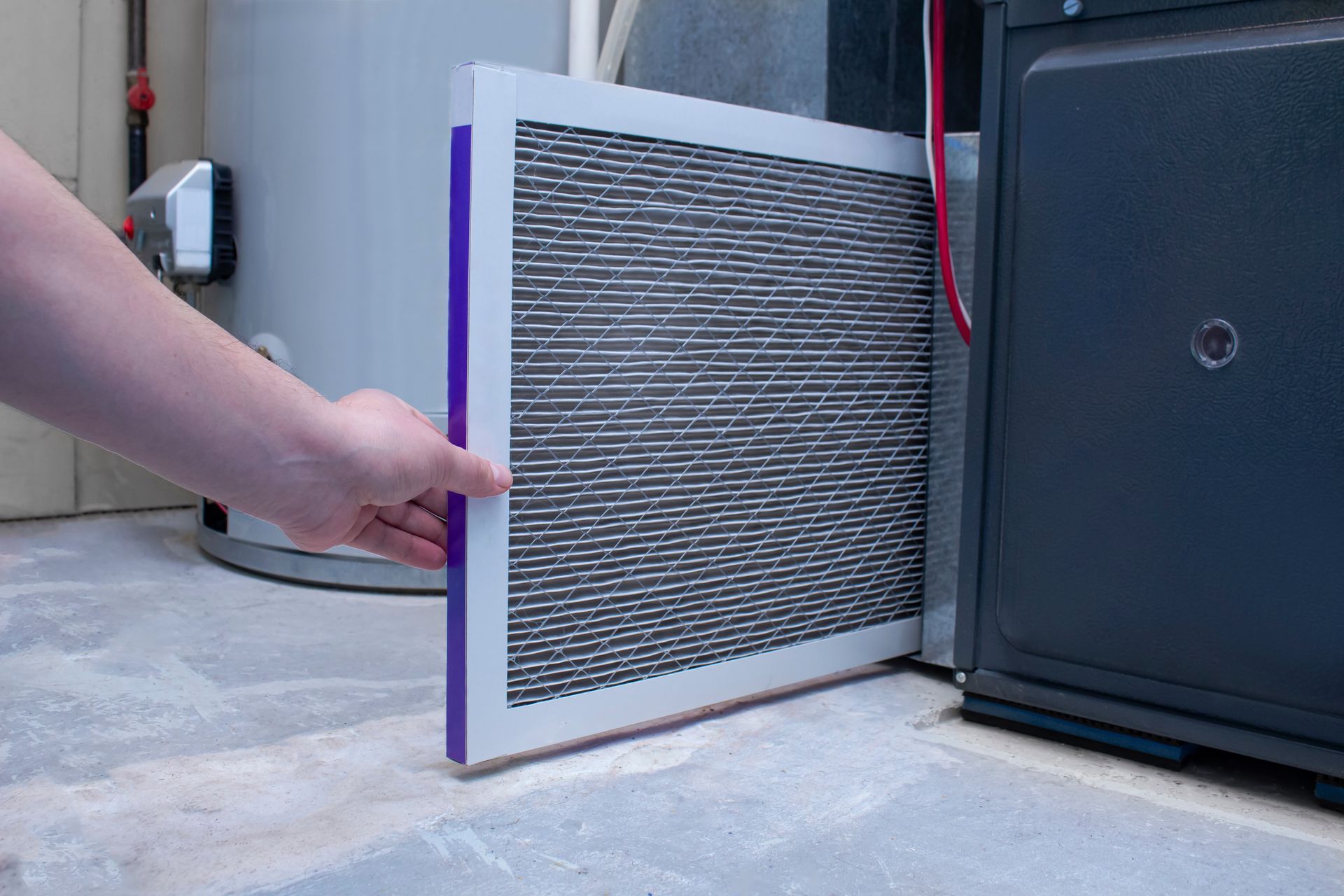 A person is holding a filter in front of a furnace.