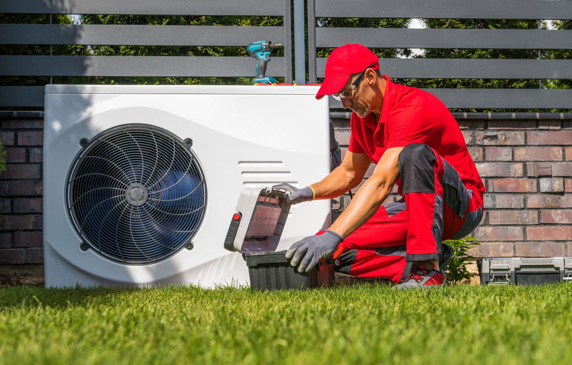 A man is working on a heat pump in a backyard.