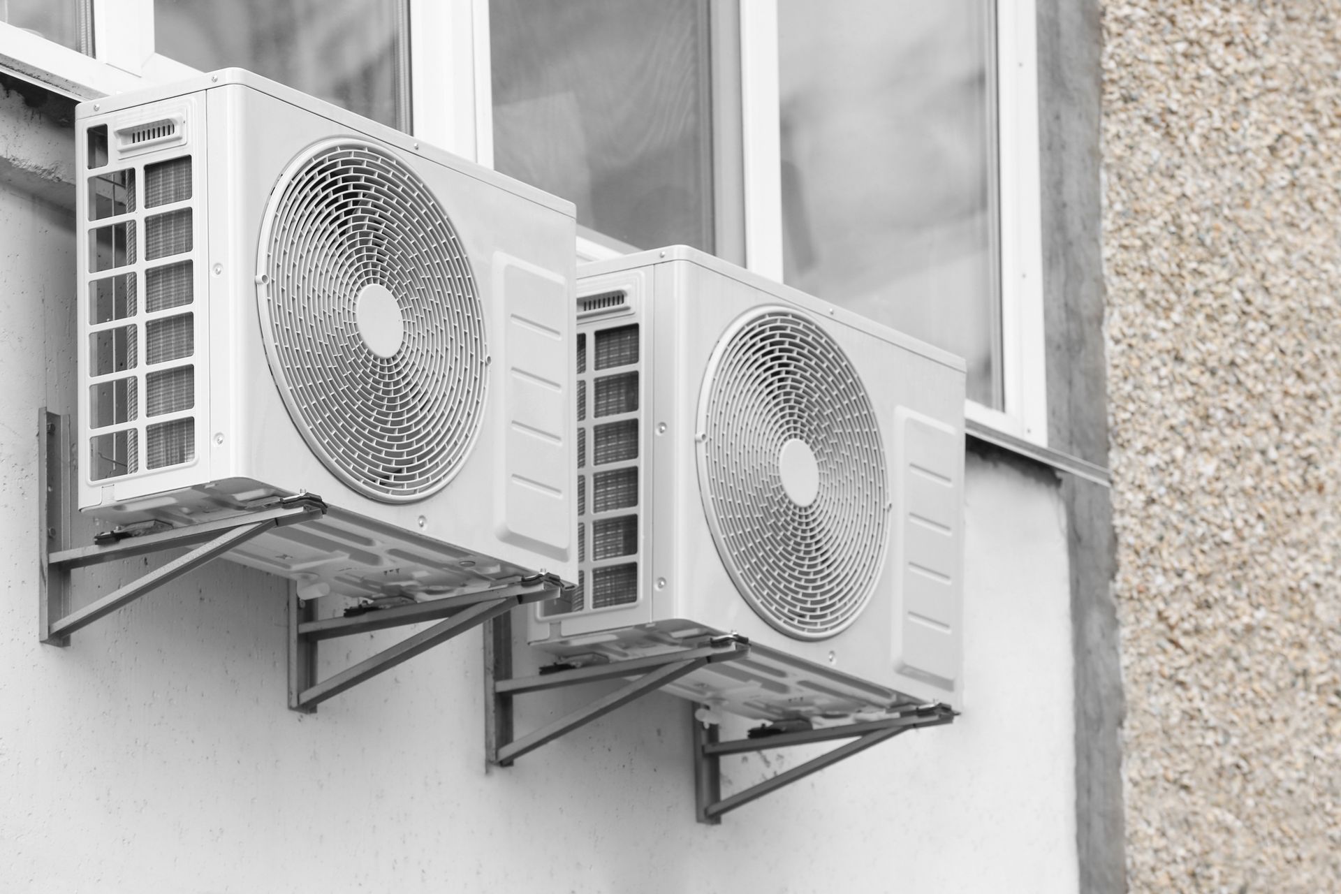 Two air conditioners are mounted on the side of a building.