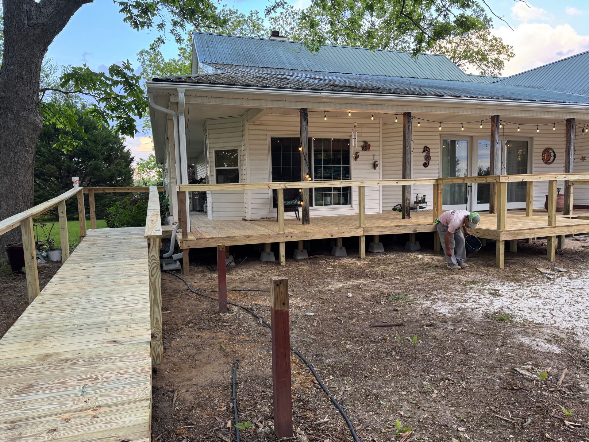 Wooden deck with ramp, house raised on supports, person working underneath.