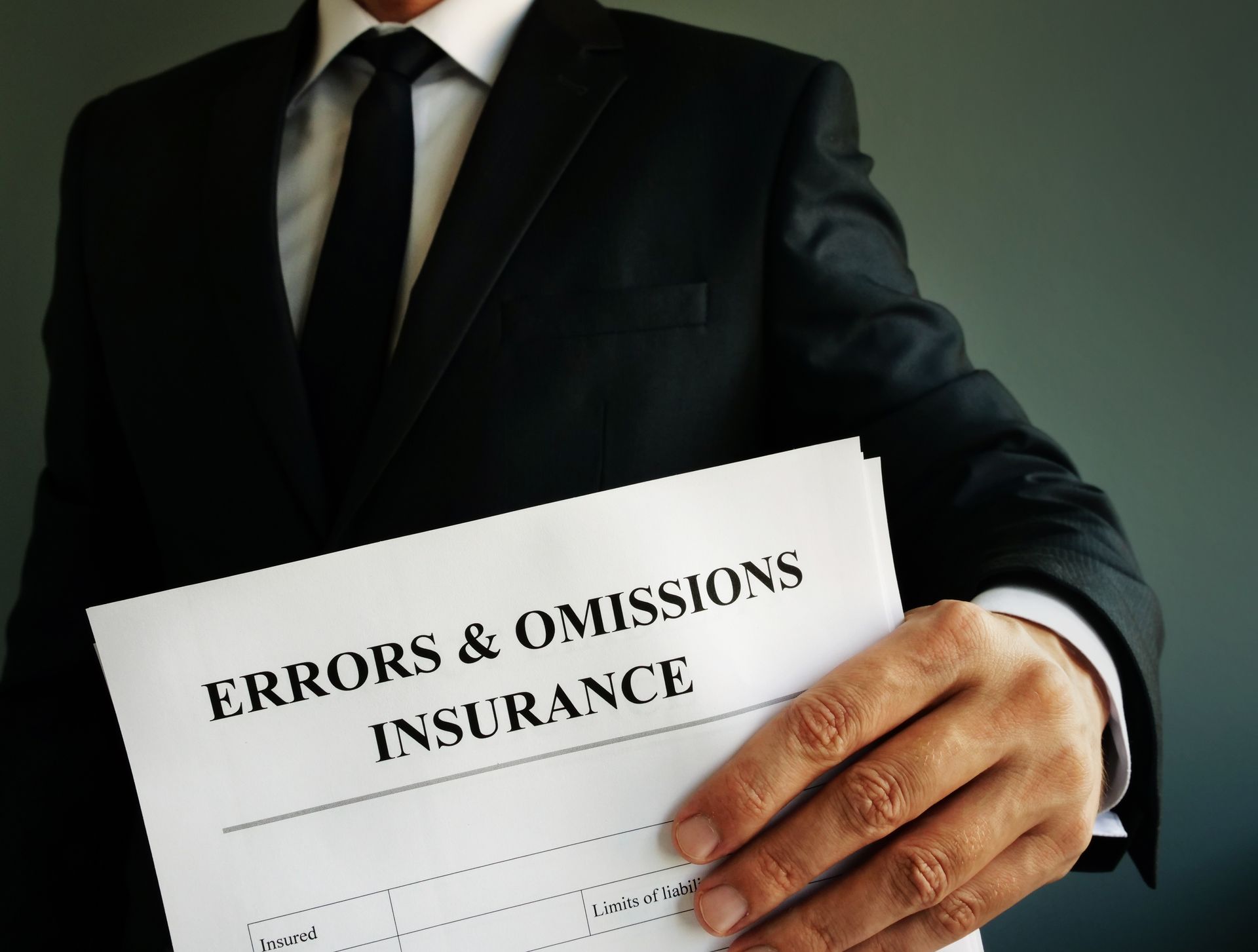 A businessman in a suit and tie holding an errors and omissions insurance document A businessman in a suit and tie holding an errors and omissions insurance document