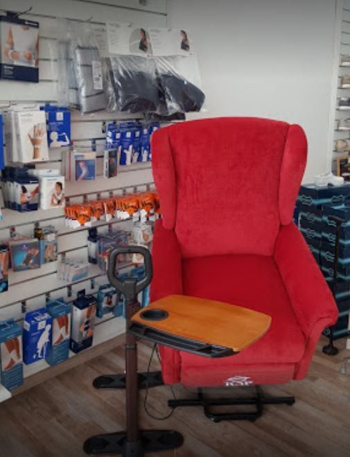 Sedia da ufficio rossa con tavoletta di legno per scrivere, in una corsia di un negozio, con prodotti esposti sugli scaffali 