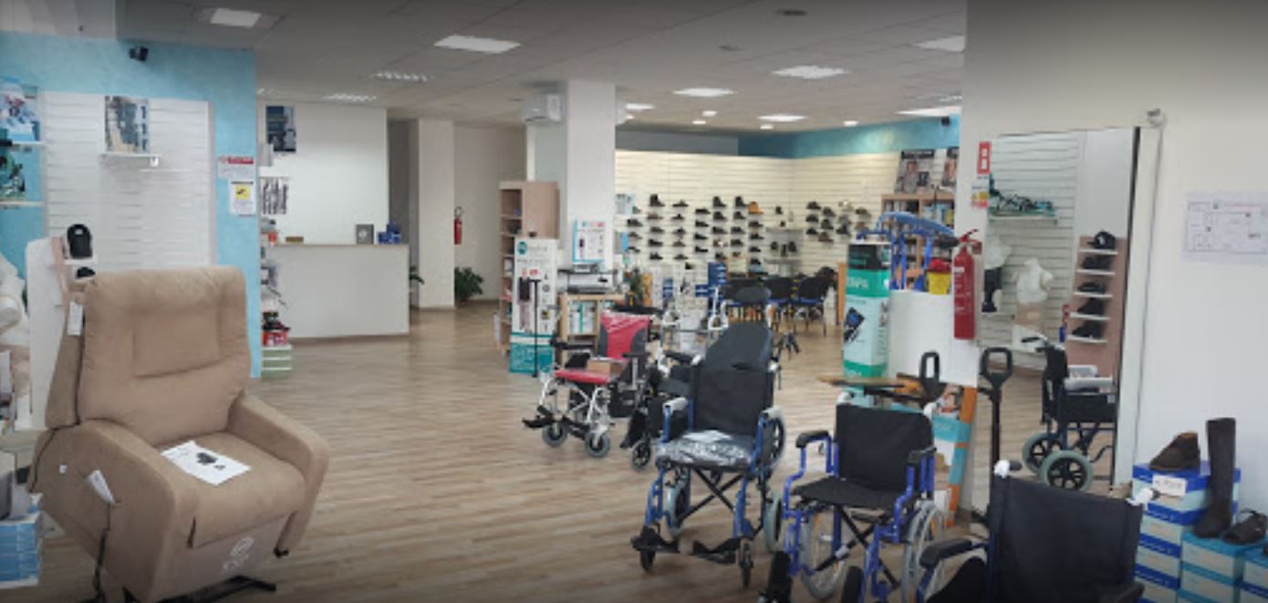 Luminoso showroom di forniture mediche con poltrone reclinabili, deambulatori, sedie a rotelle e scaffali espositivi.