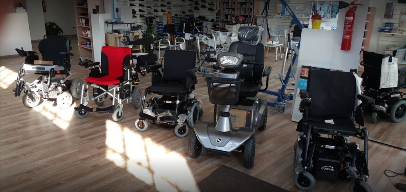Showroom con diversi scooter per disabili e sedie a rotelle elettriche su un pavimento in legno.