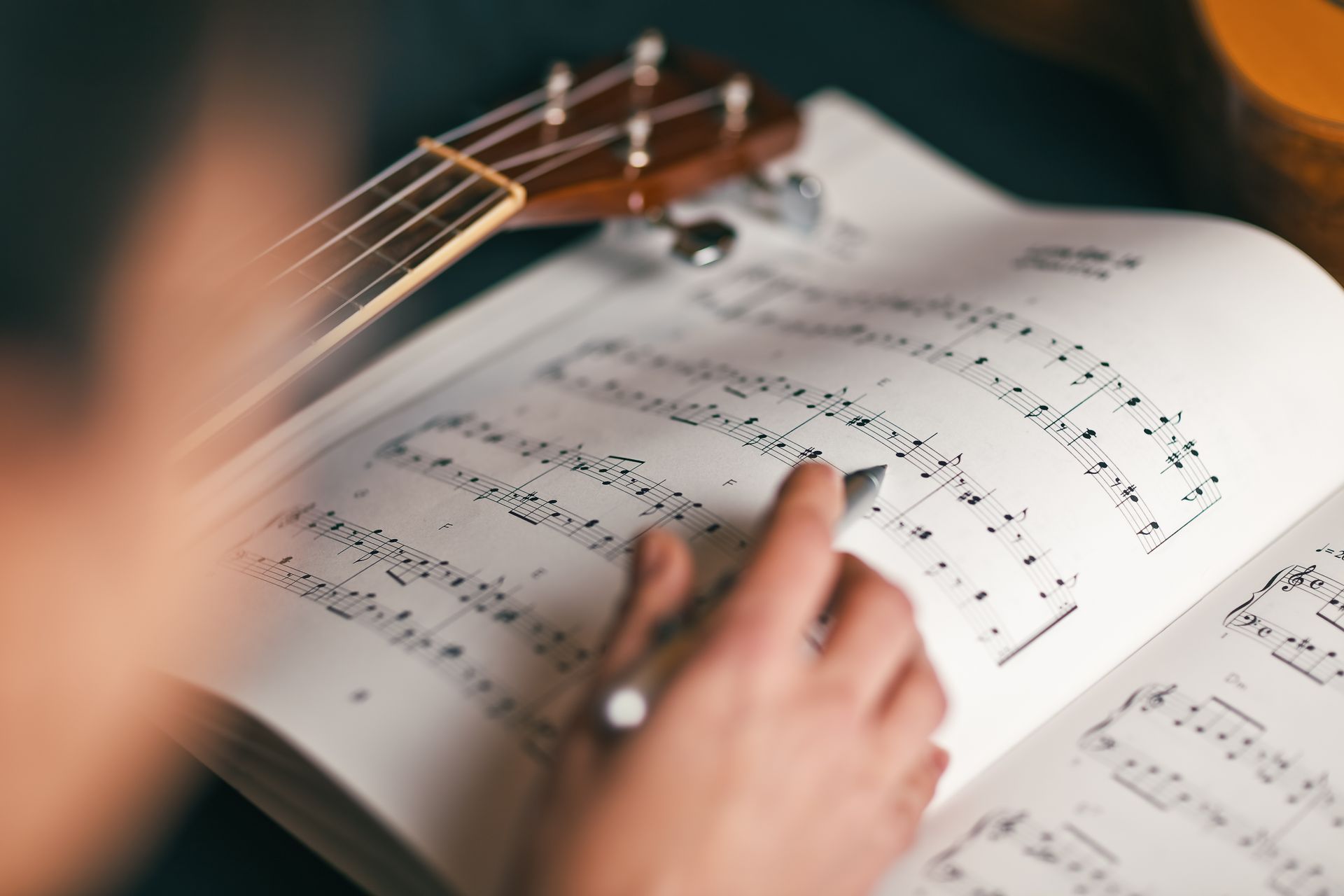 Hands turning pages of sheet music beside a guitar neck Hands turning pages of sheet music beside a guitar neck