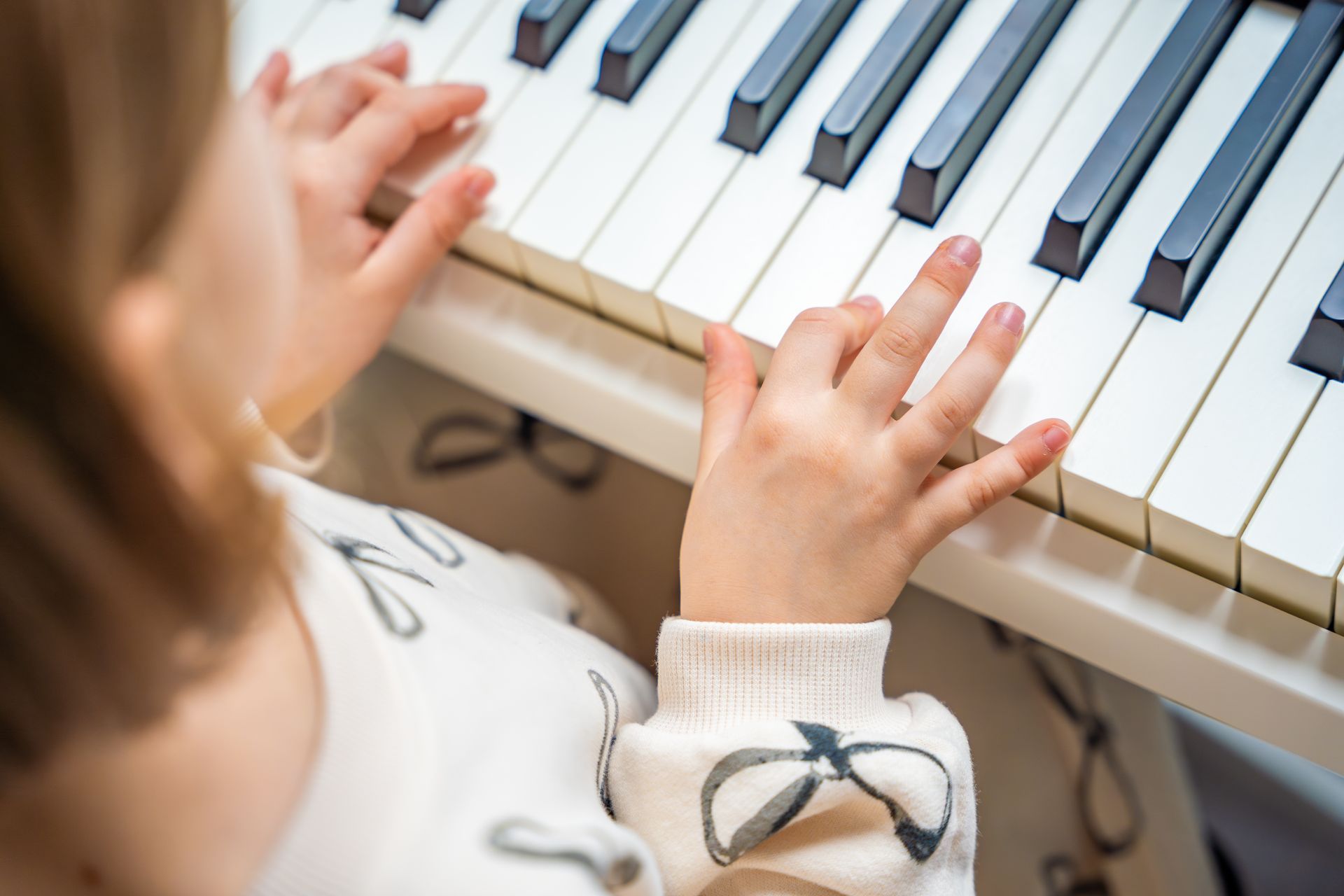 Child playing piano keys close-up, hands on white and black keys Child playing piano keys close-up, hands on white and black keys