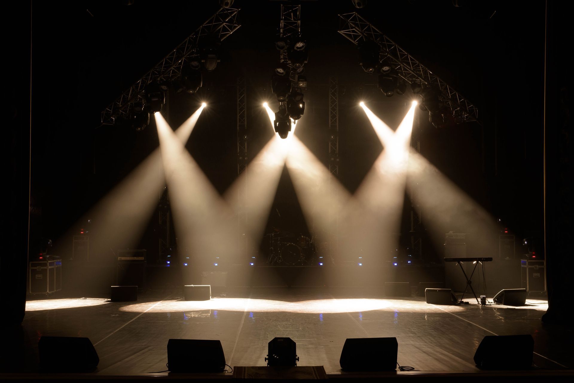 Empty concert stage lit by three bright spotlights in a dark venue Empty concert stage lit by three bright spotlights in a dark venue