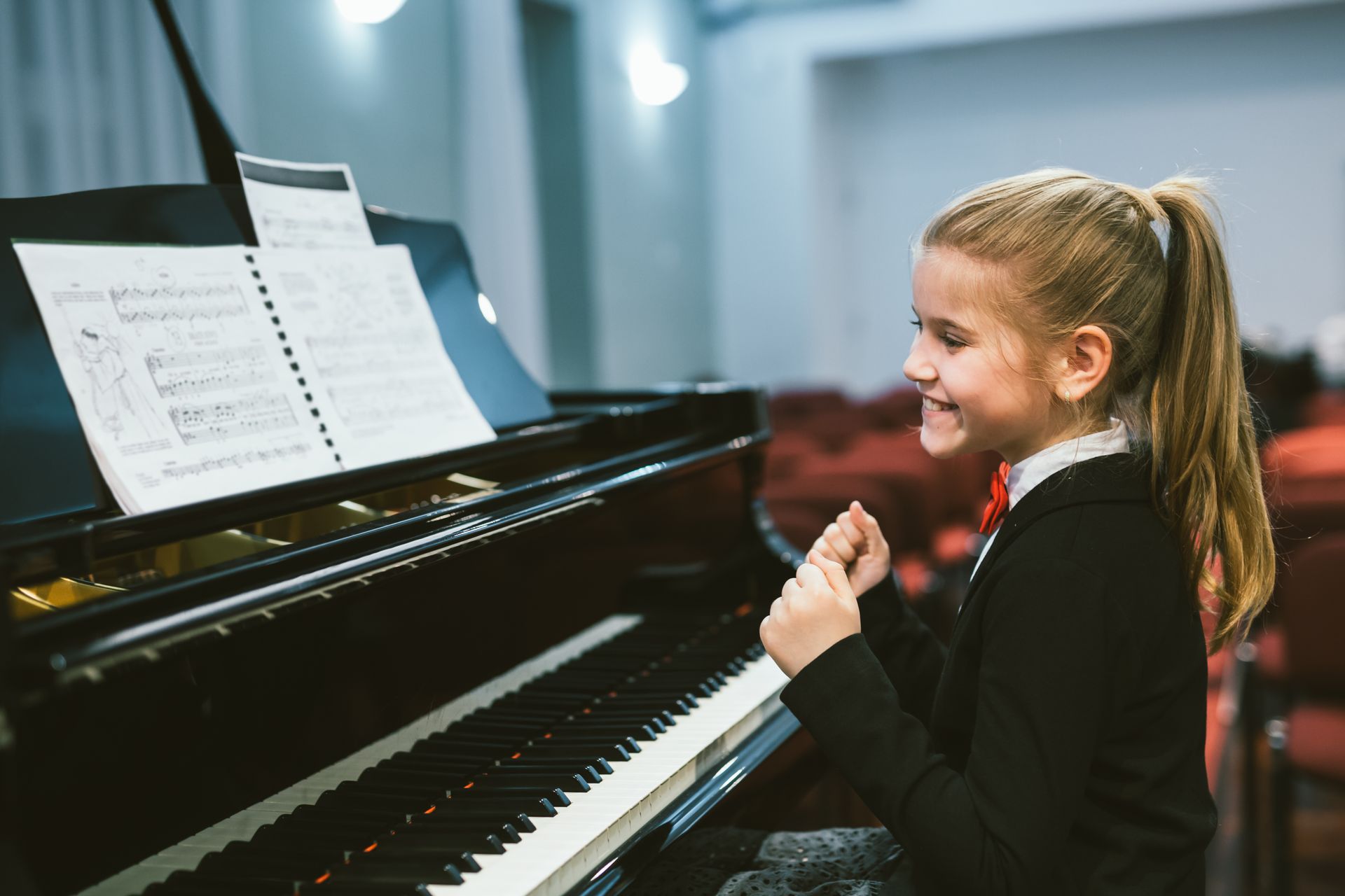 Young girl smiling at a piano while reading sheet music in a bright music room Young girl smiling at a piano while reading sheet music in a bright music room