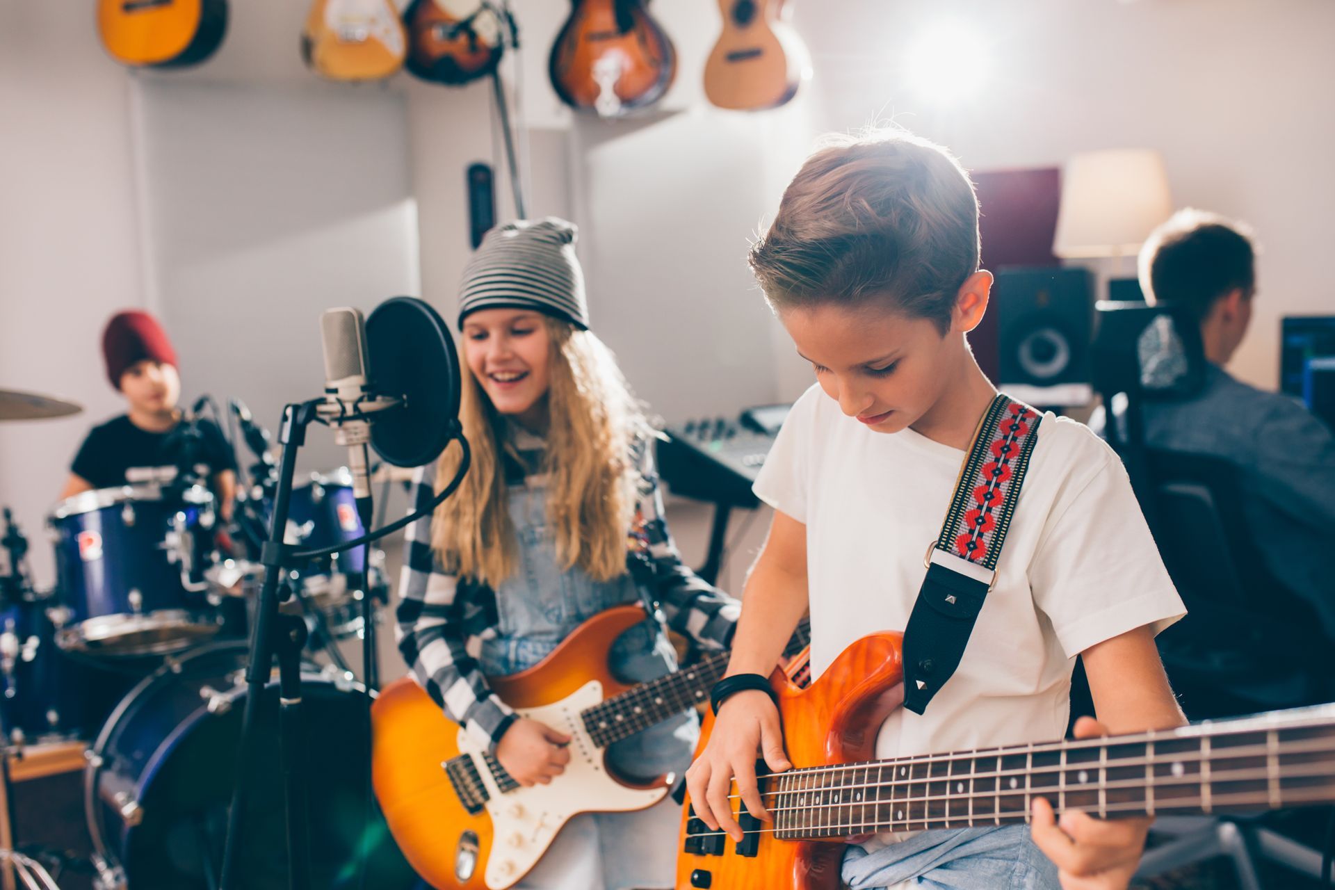 Musicians playing guitars and drums in a bright rehearsal studio, with one singer at a microphone Musicians playing guitars and drums in a bright rehearsal studio, with one singer at a microphone