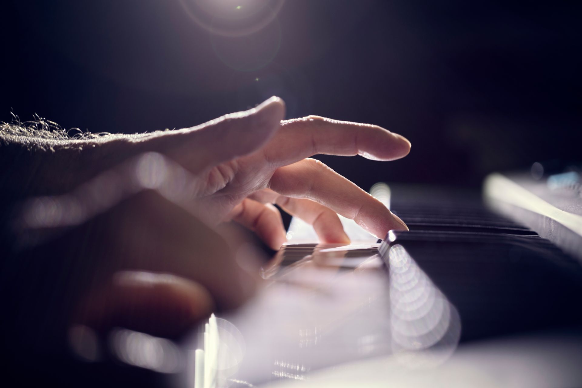 Hand playing piano keys under soft stage light Hand playing piano keys under soft stage light