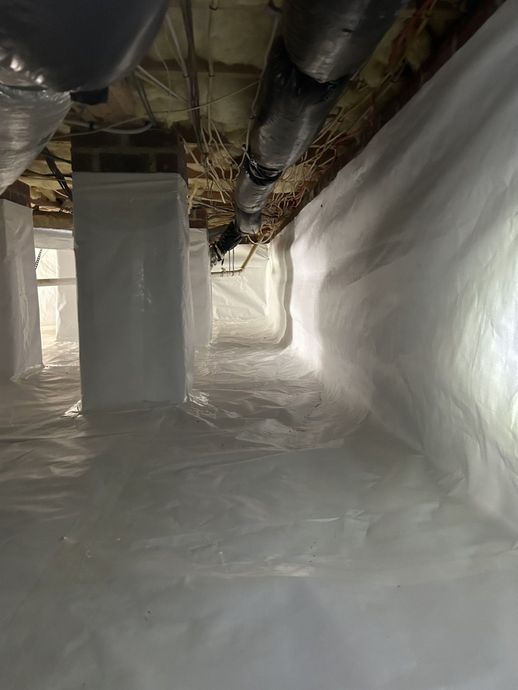 A crawl space filled with plastic and pipes.