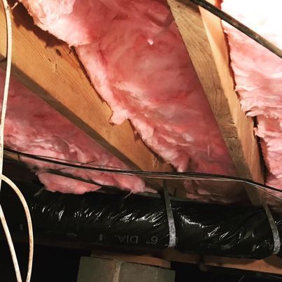 A ceiling with pink insulation and a black pipe that says 6 dia