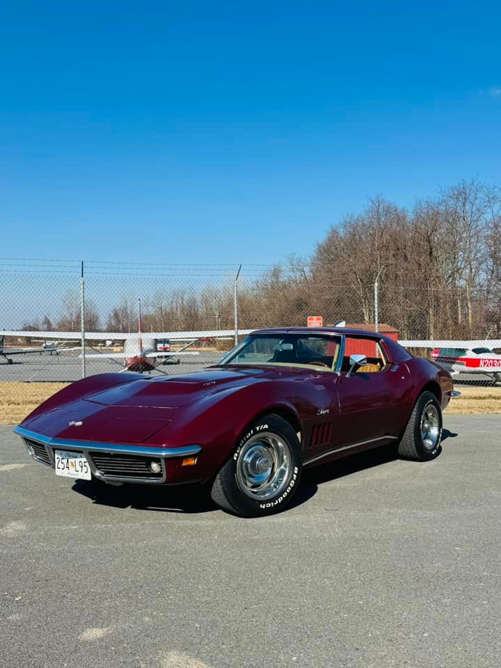 A burgundy corvette is parked in a parking lot.