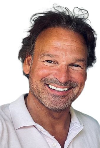 Jean Paul van der Linden met een baard lacht naar de camera terwijl hij een wit overhemd draagt.