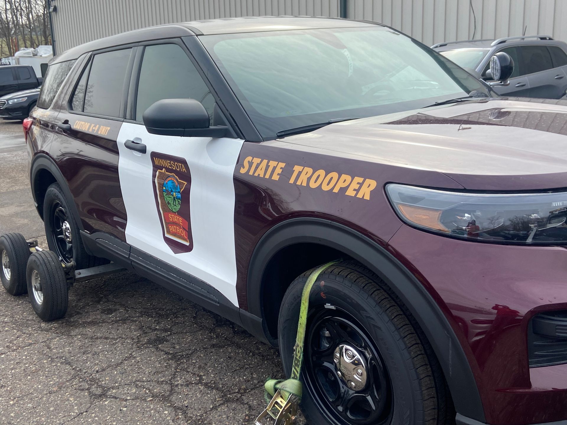 Maroon and white state trooper SUV parked in a lot with a boot on the front wheel