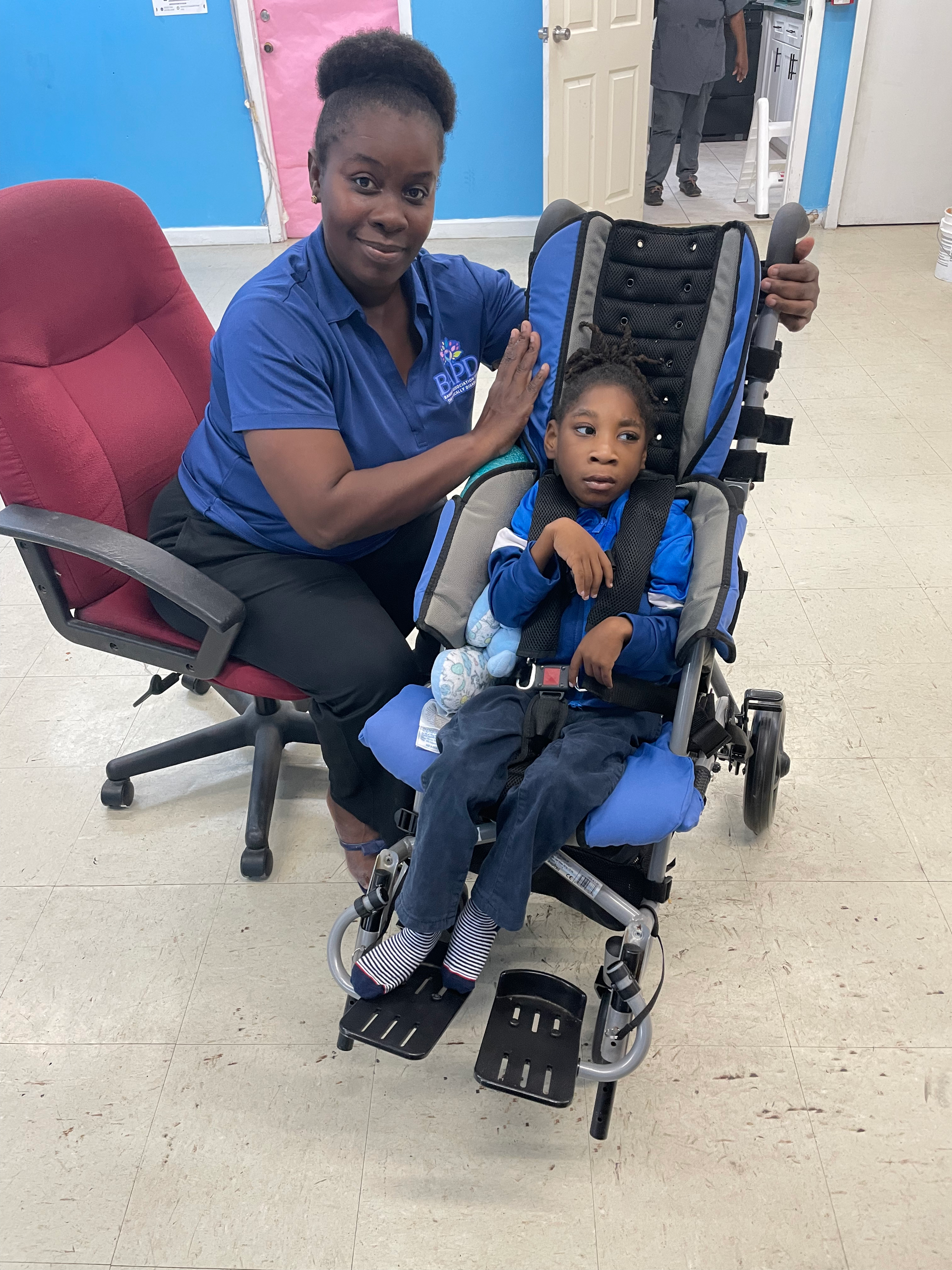 A woman is sitting next to a child in a wheelchair.