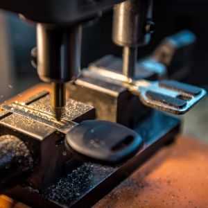 Close-up of a key being cut on a key-cutting machine, with metal shavings on the work surface