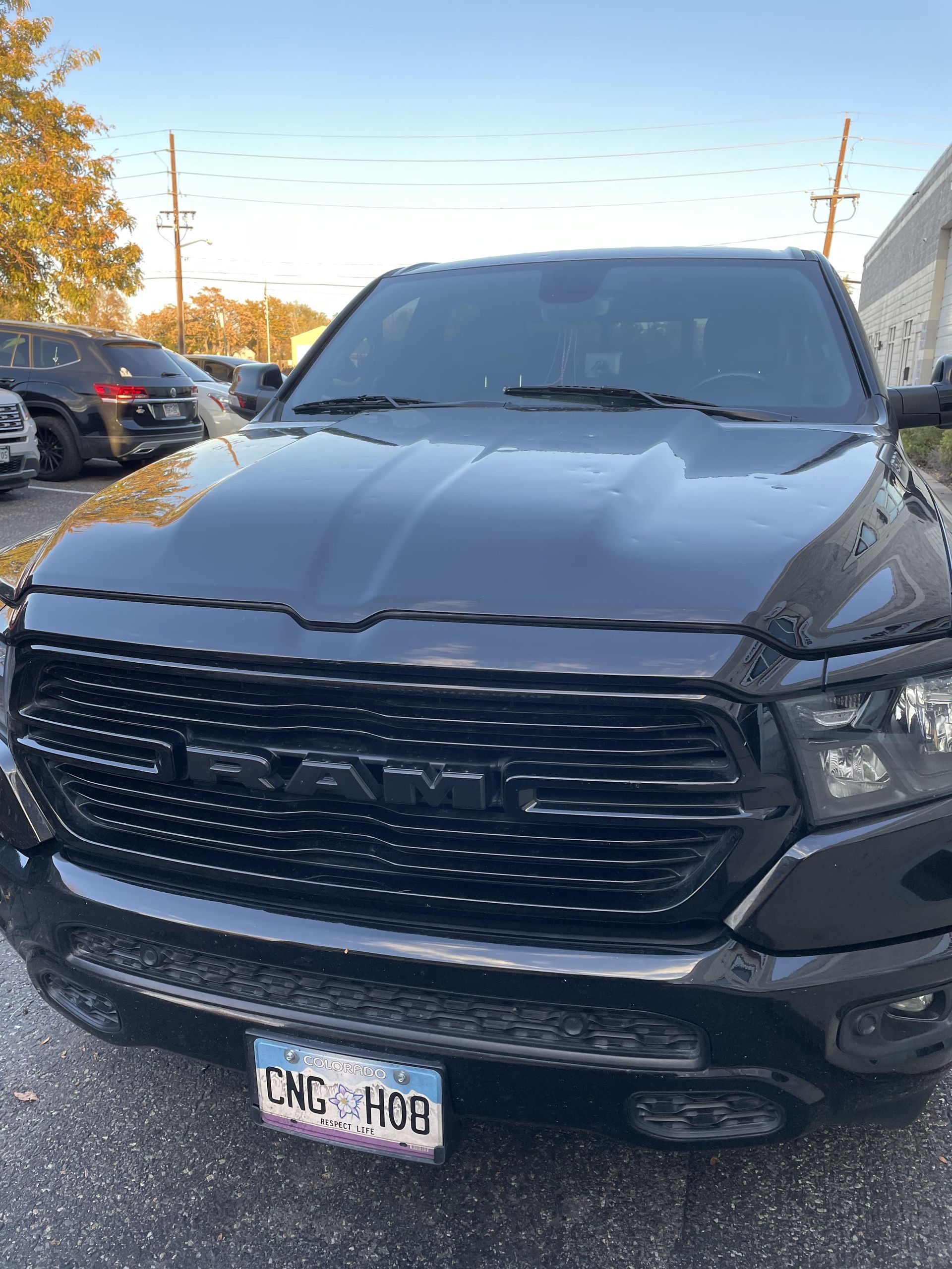 Black GMC truck parked outdoors in a lot, front view with visible license plate.