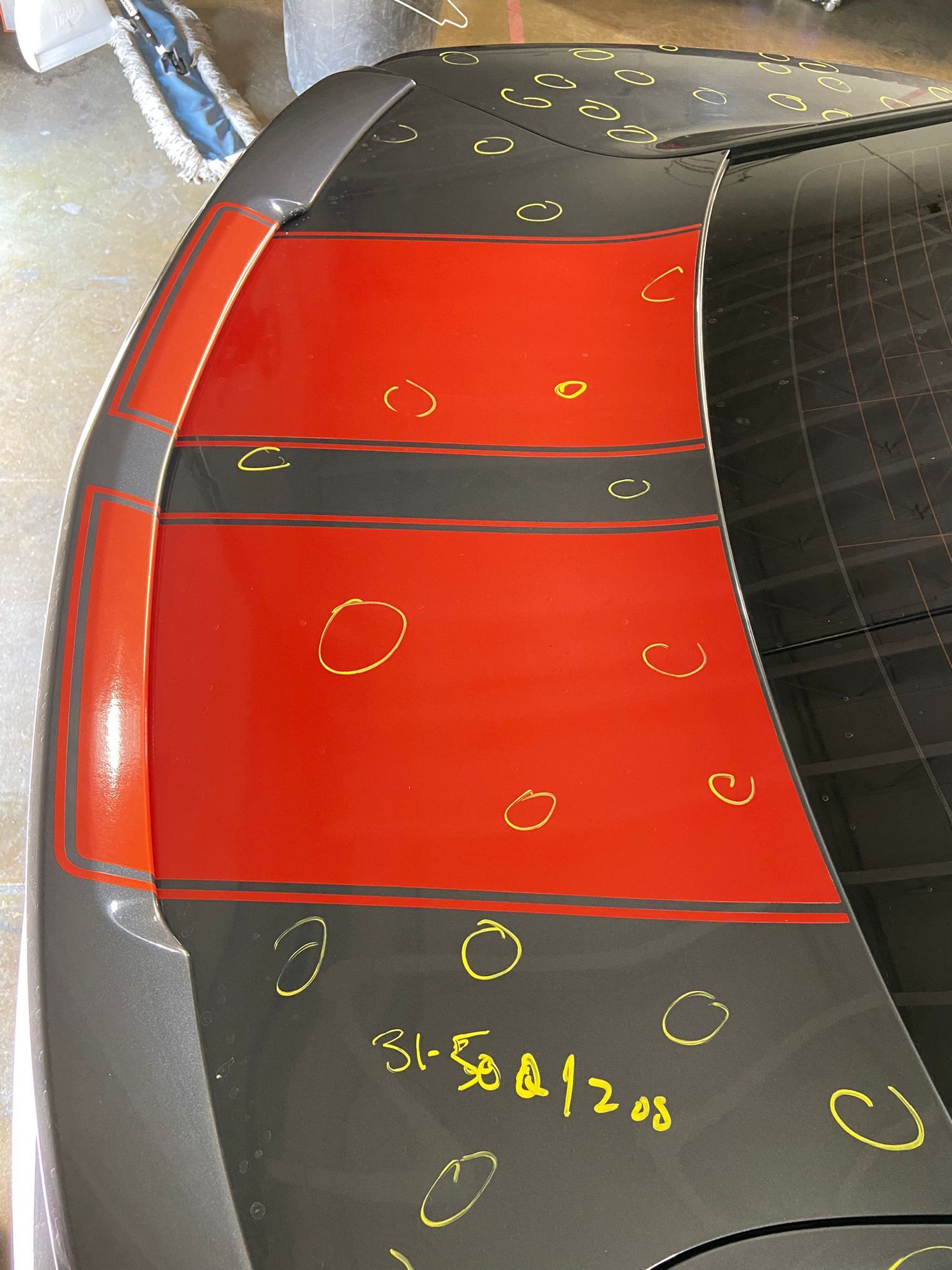 Red and black car roof with yellow inspection marks and measurements outlined in chalk