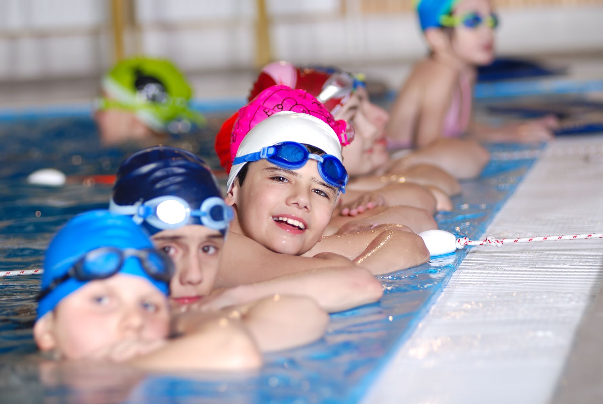 A group of kids hanging out at the pool for swim lessons