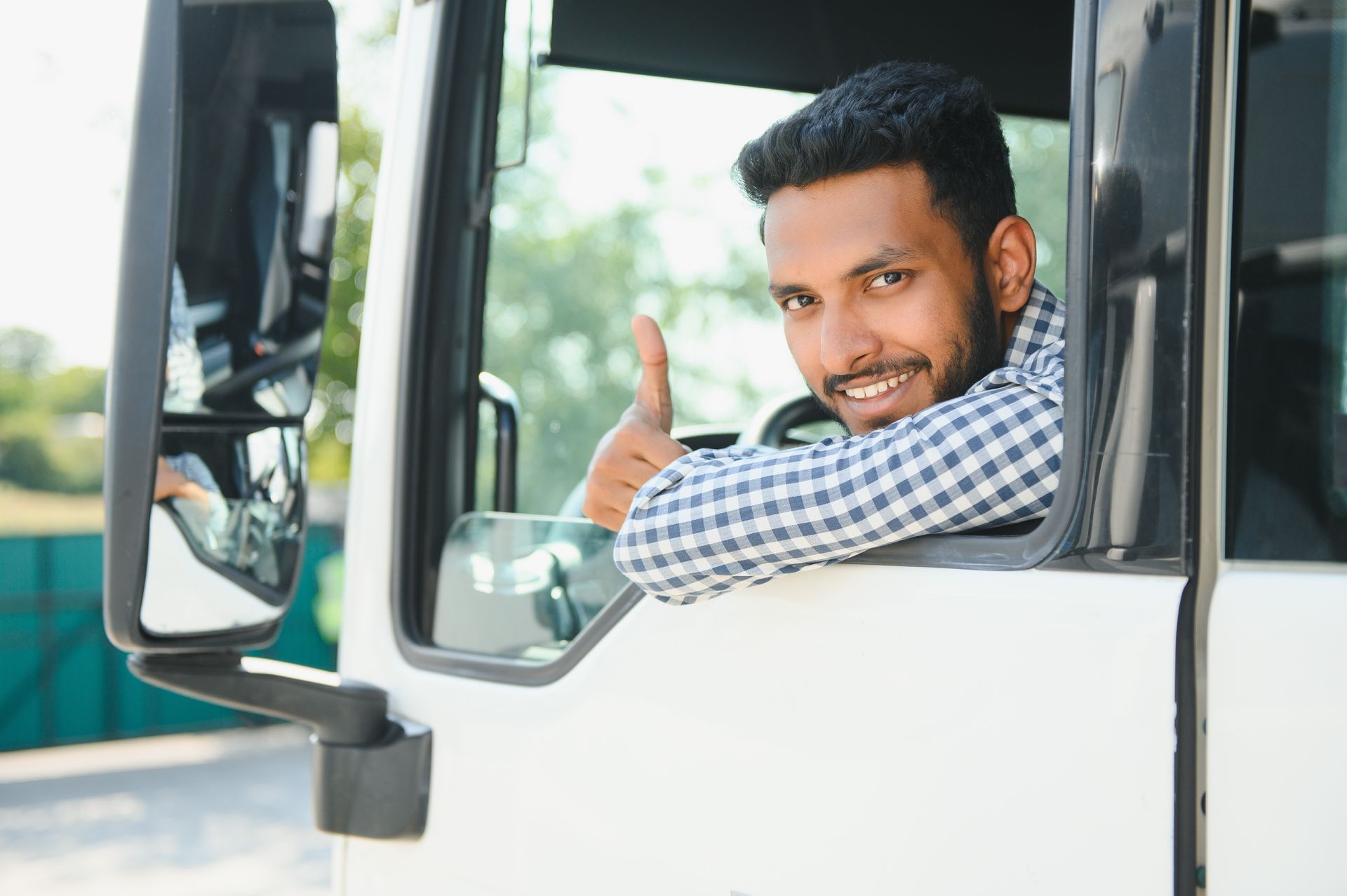 Man in truck cab gives thumbs up.