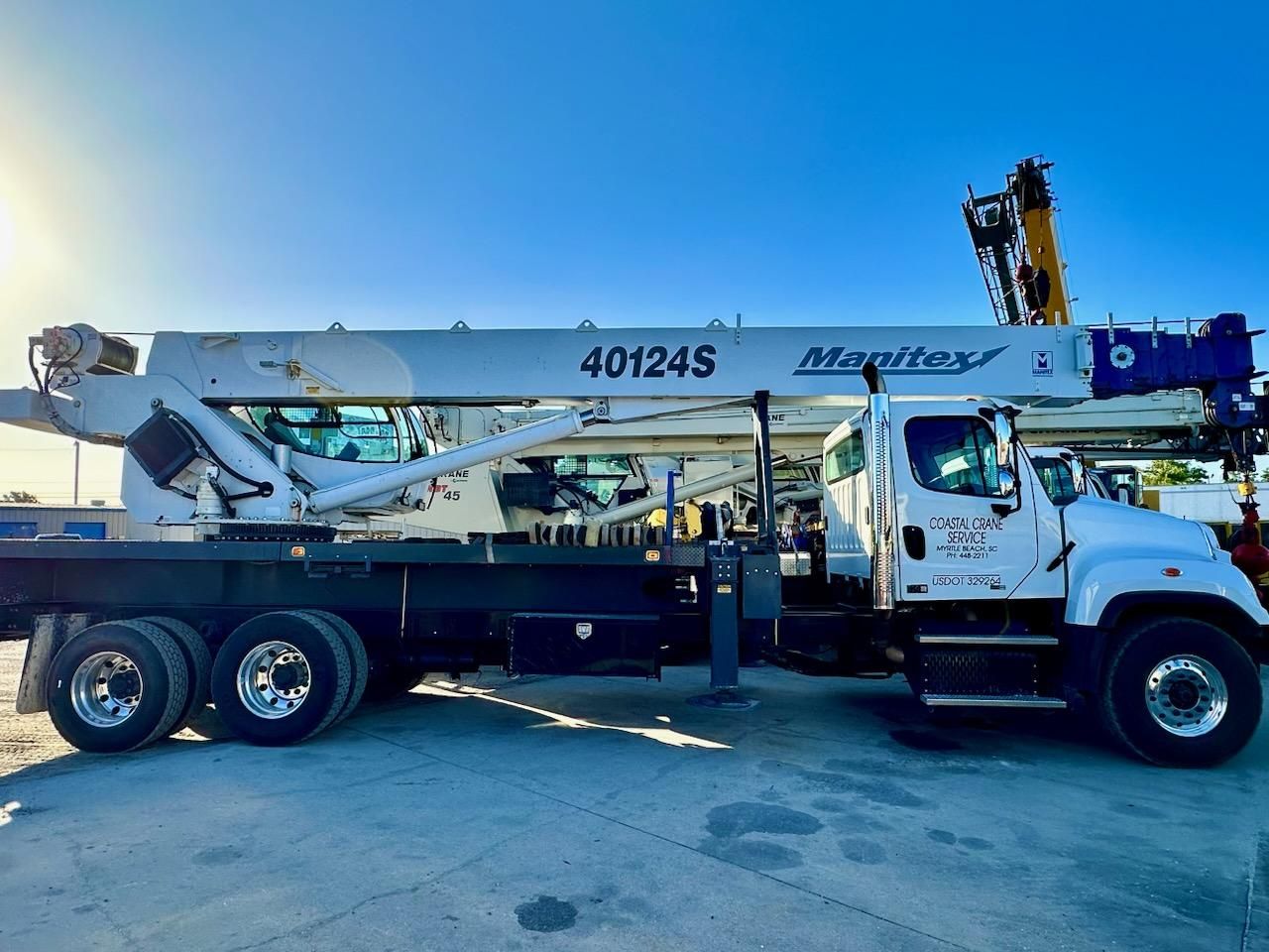 White utility truck with a boom lift parked outdoors on a sunny day