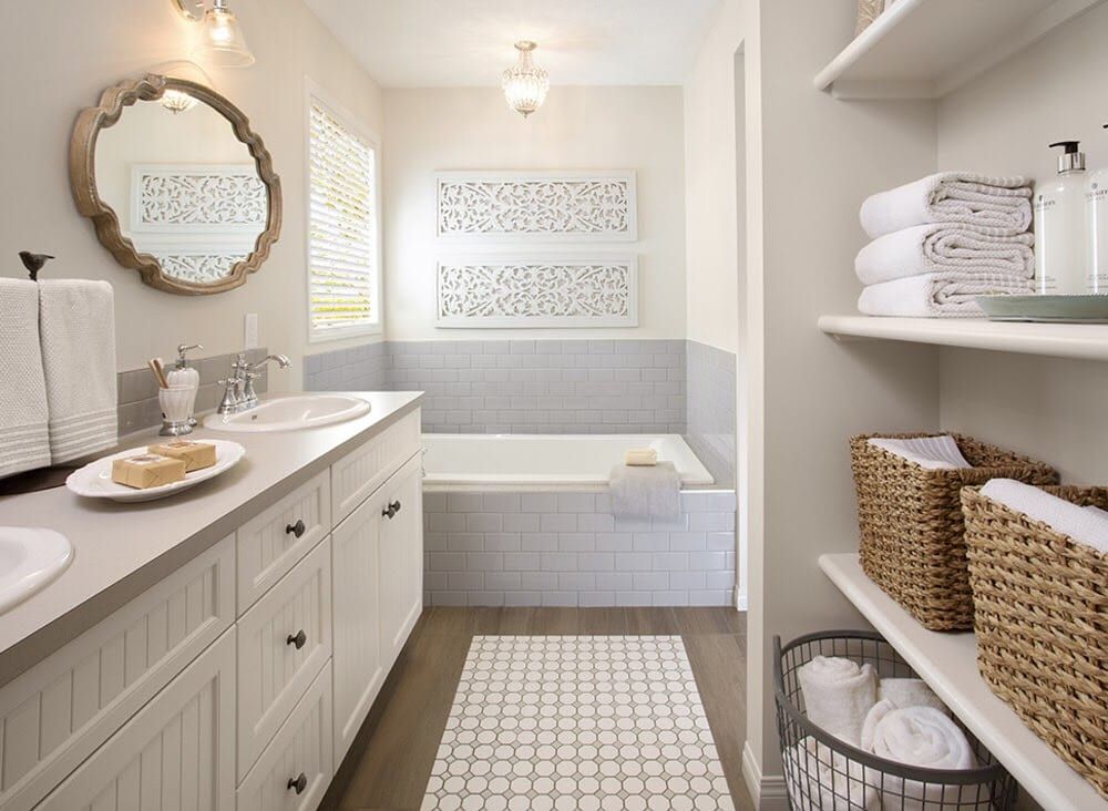 A bathroom with two sinks , a tub , and wicker baskets.