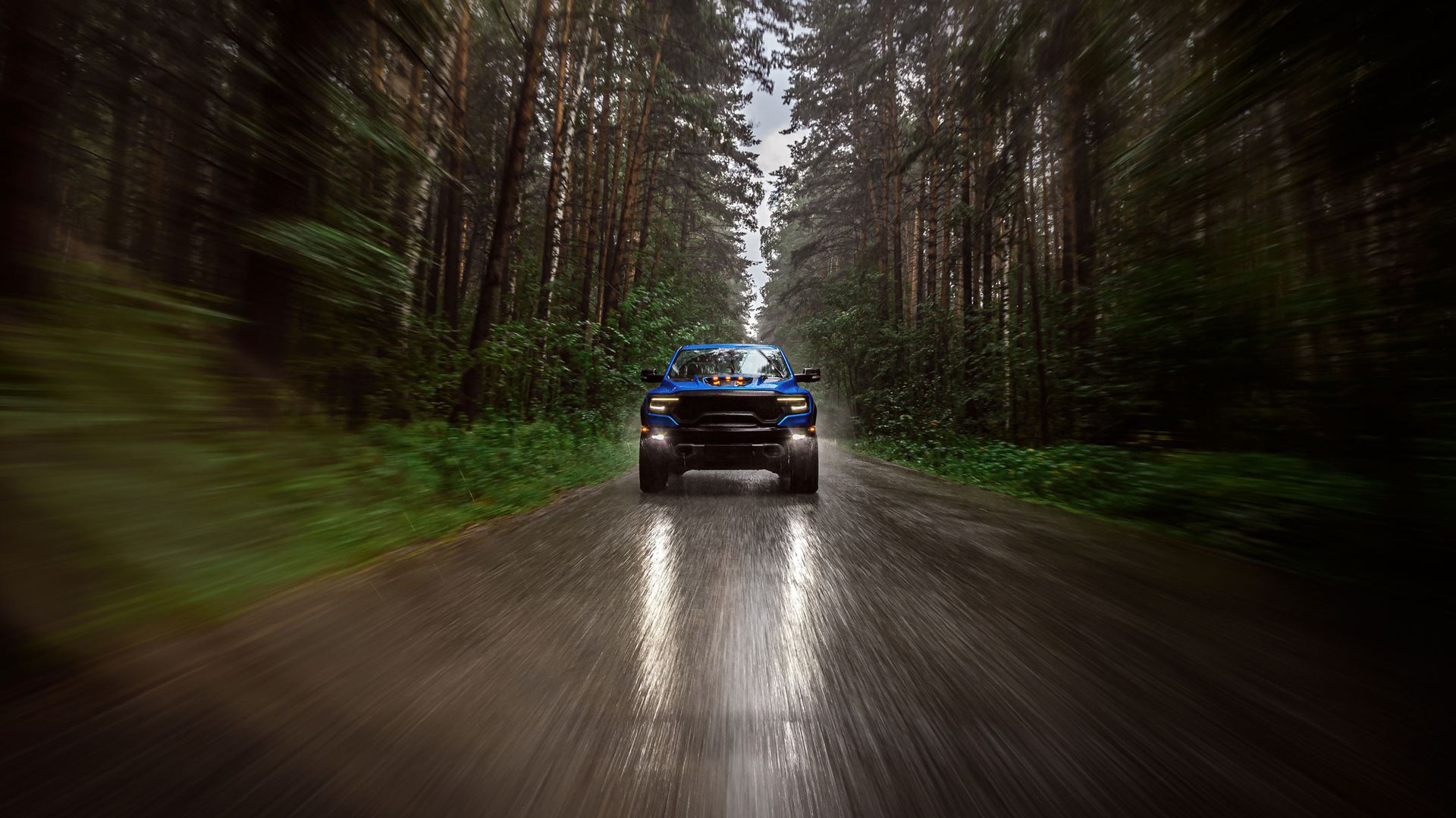 Blue truck driving on a wet road through a forest; motion blur effect. Blue truck driving on a wet road through a forest; motion blur effect.