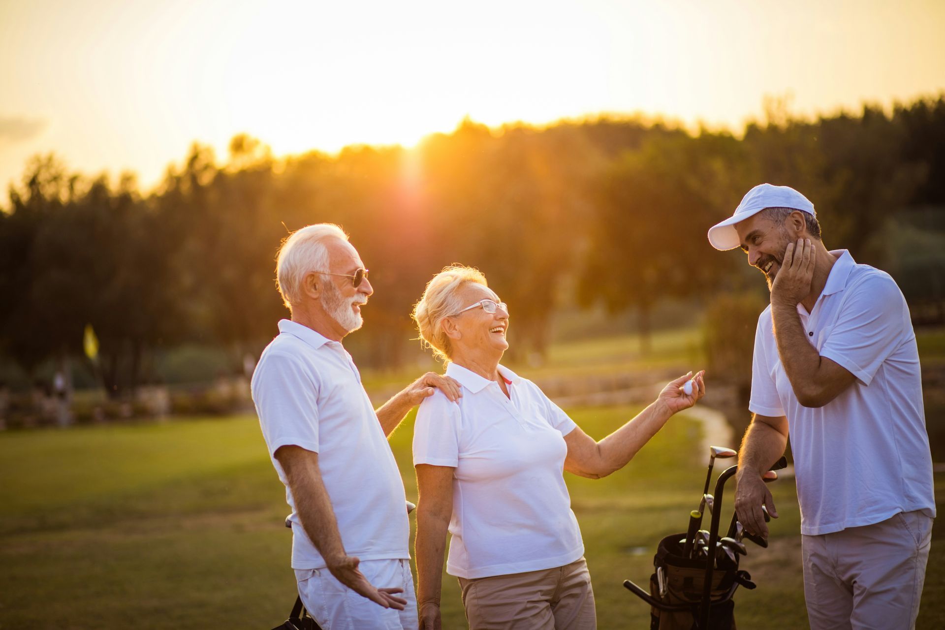 A group of elderly people are standing on a golf course talking to each other.