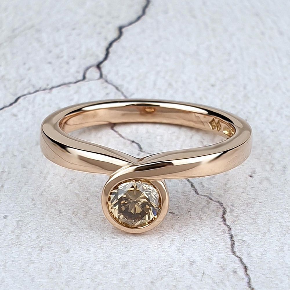 An infinity engagement ring in 18ct red gold, set with a round brown diamond