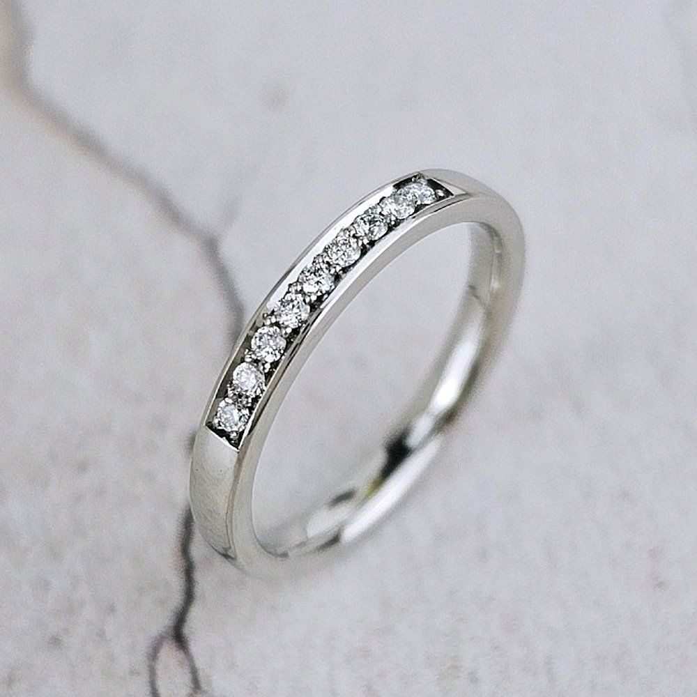 A wedding ring with 9 diamonds set on the top.