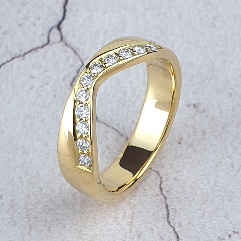 a gold fitted wedding ring shaped on one side and straight on the other side.