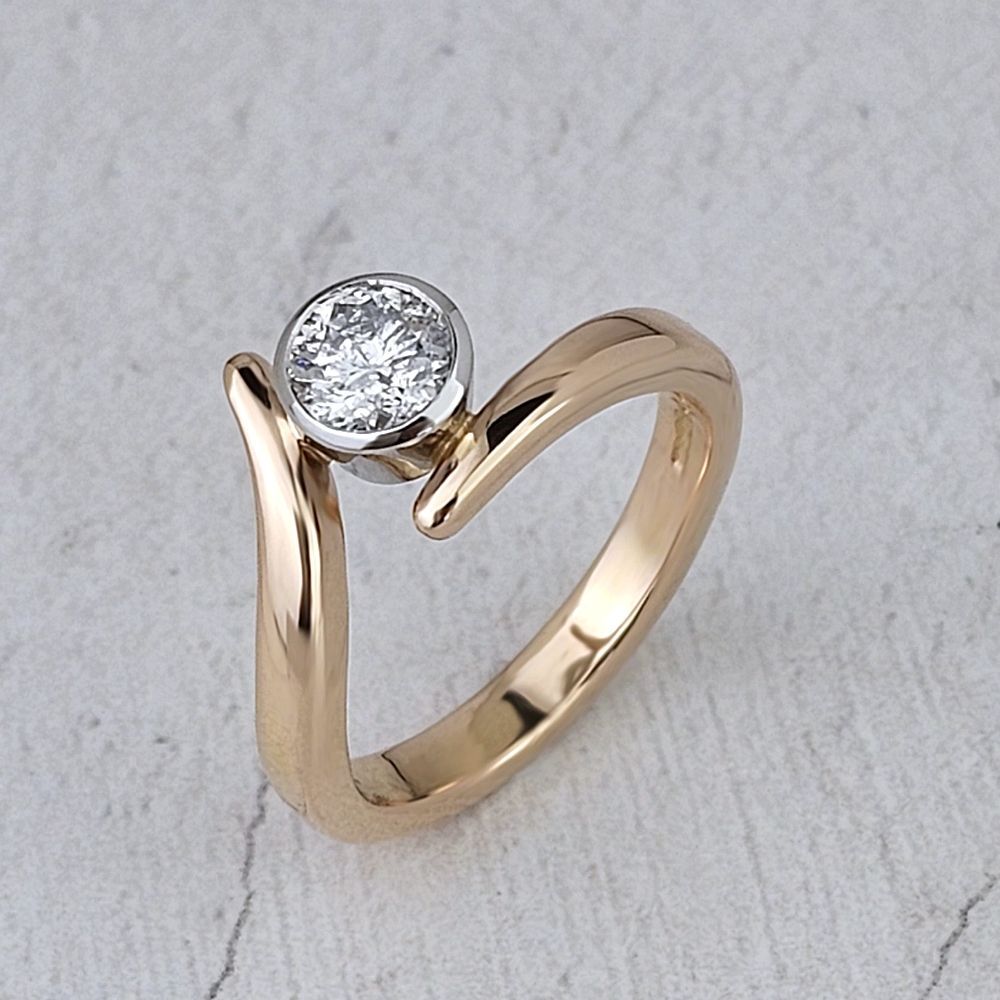 A Flick engagement ring with a round diamond in platinum on a yellow gold band