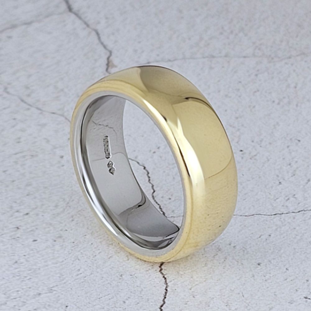 A man's yellow gold court wedding band that is lined with platinum.