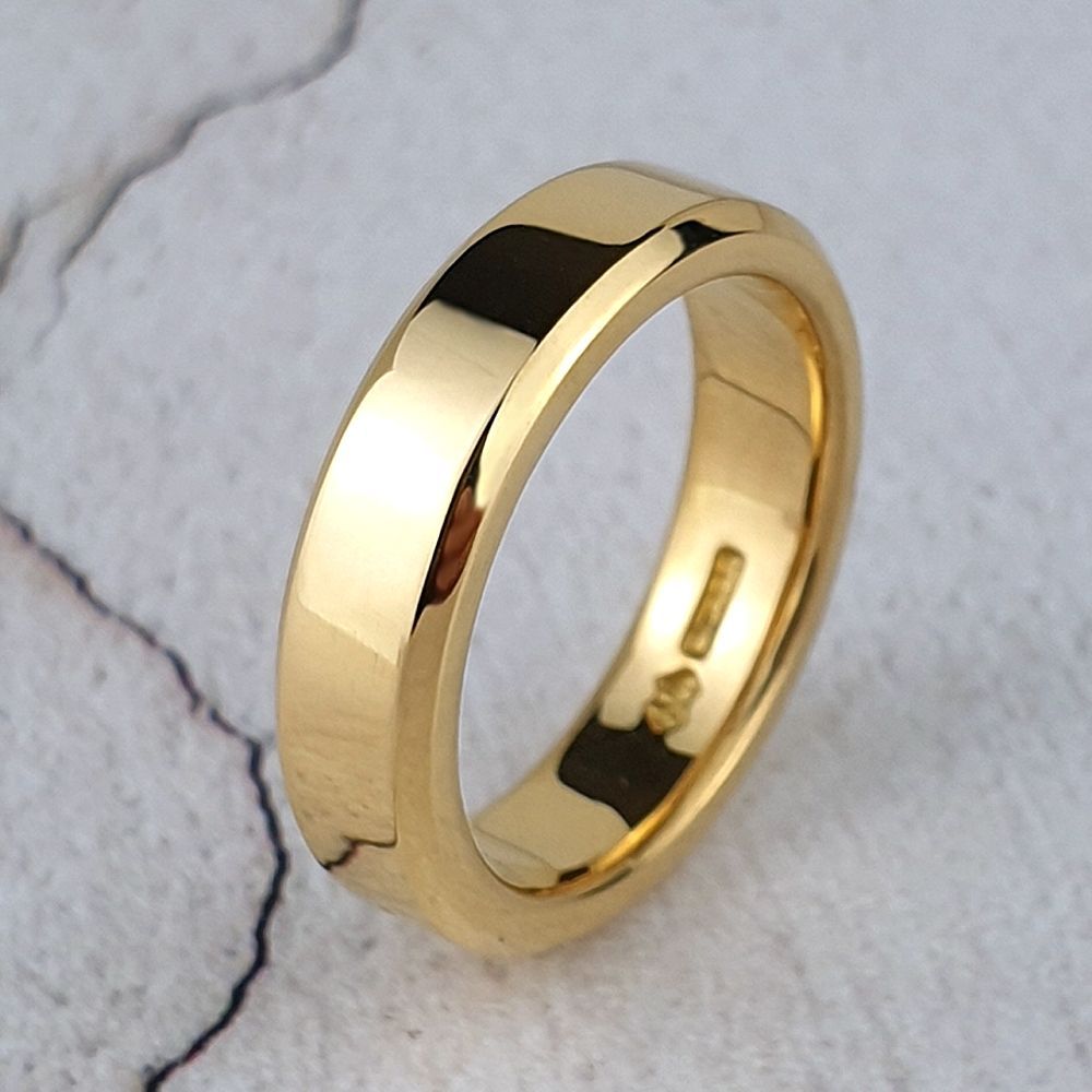 A yellow gold weding ring with bevelled edges edges