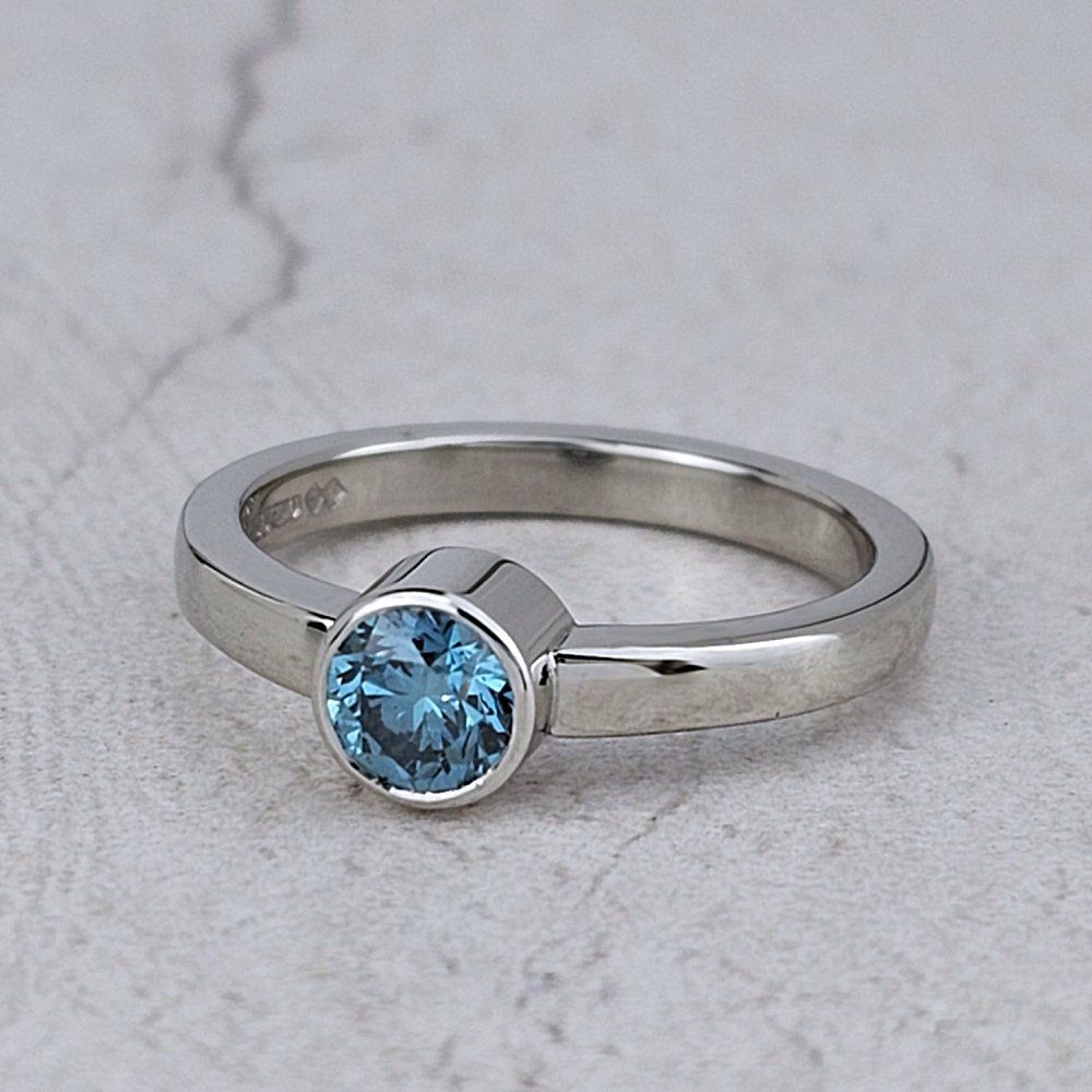 A platinum engagement ring with a blue diamond