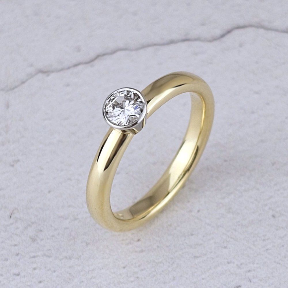 A simple single diamond ring in gold with a platinum bezel setting