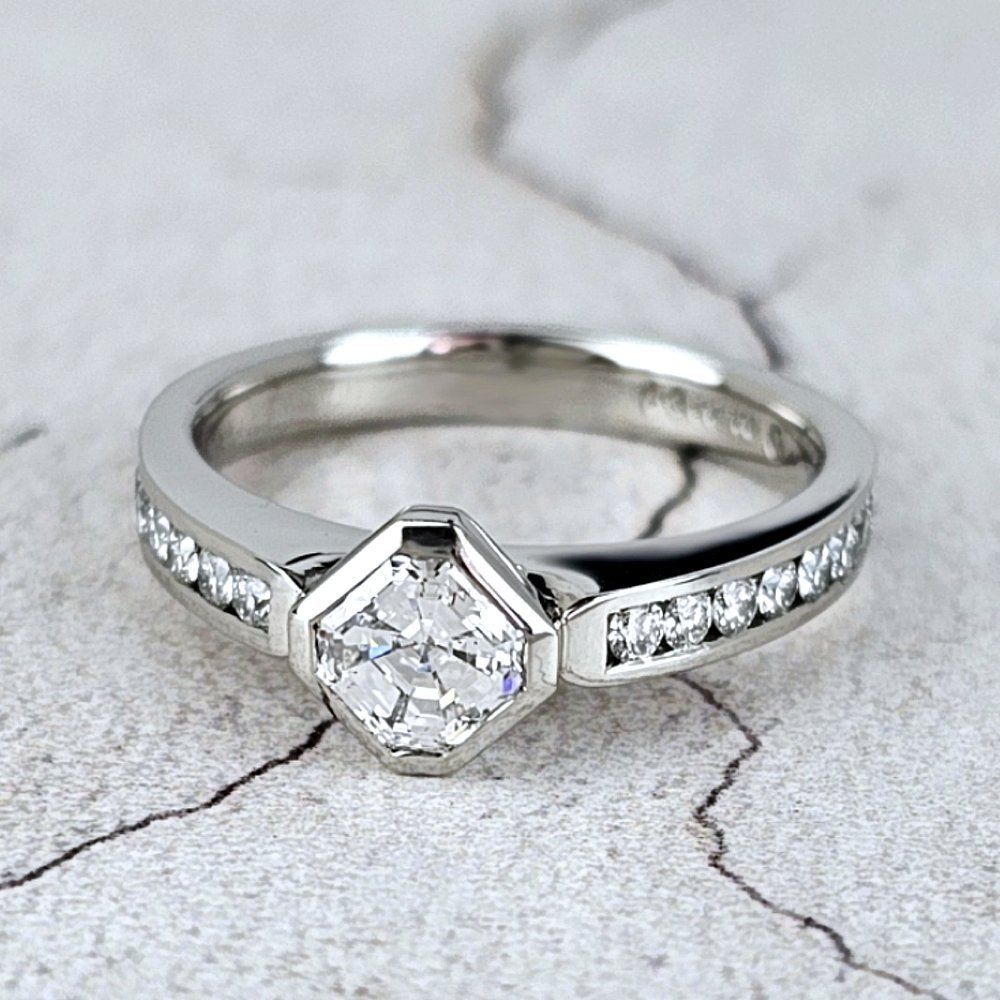 A platinum engagement ring with an Asscher diamond, and small round diamonds in the band