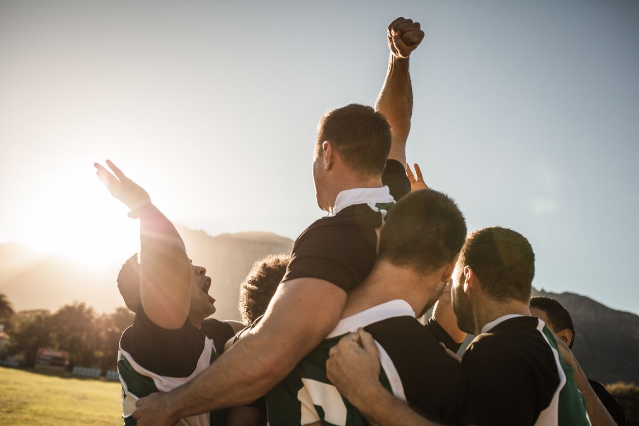 El equipo de rugby se reúne al aire libre, celebrando