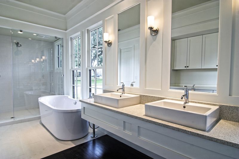 White bathroom with double sinks, a standalone tub, and a glass shower.