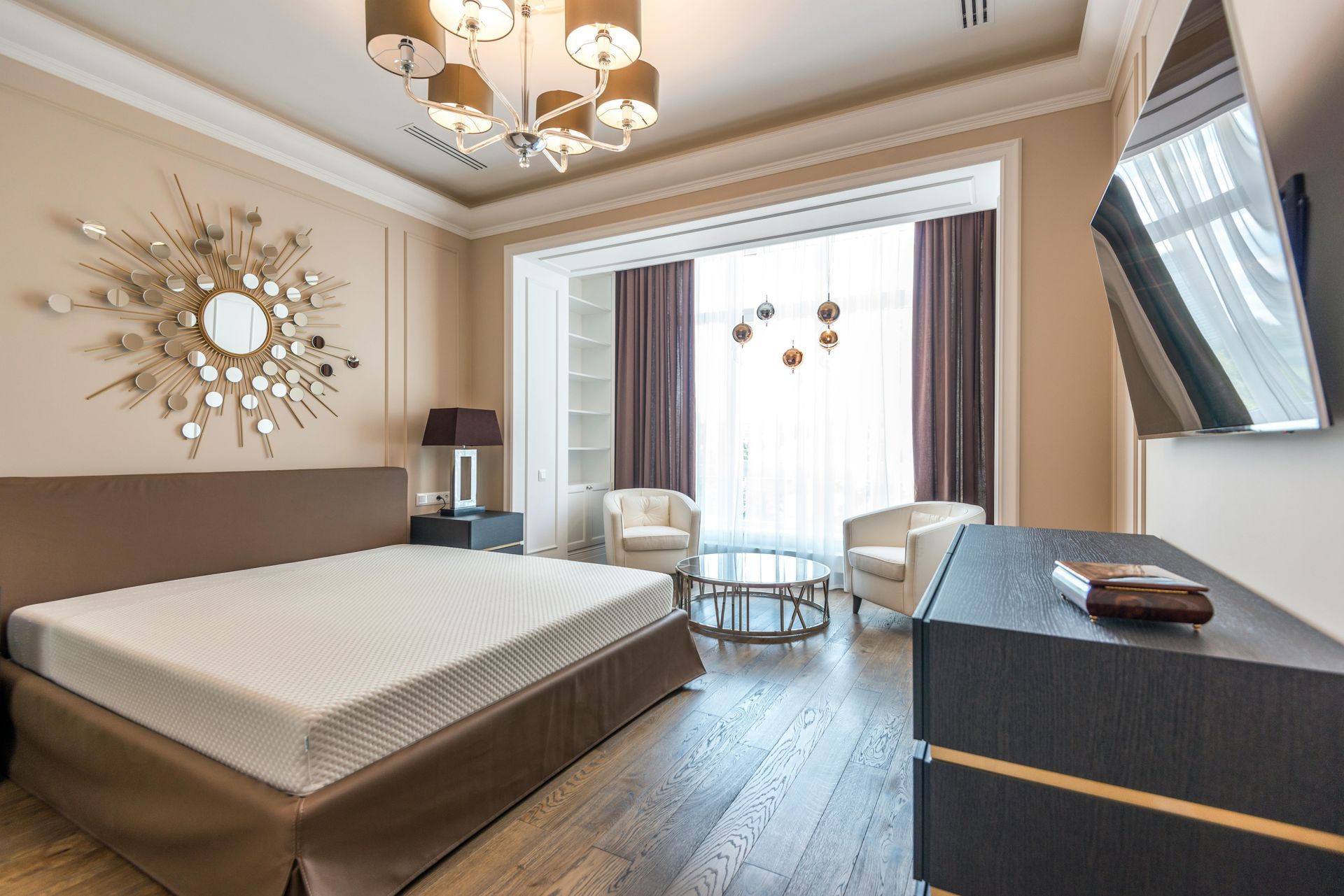 Bedroom with bed, chairs, large window, and modern decor.