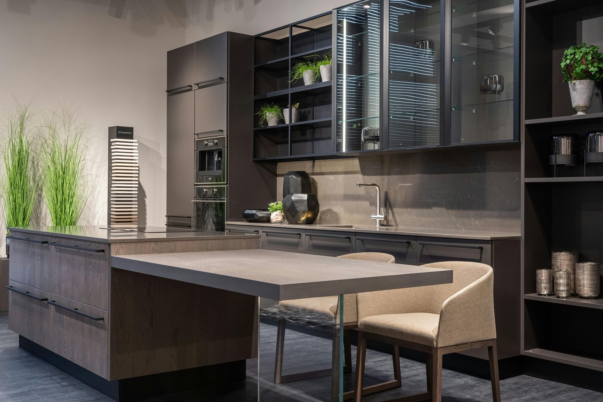 Modern kitchen with dark cabinetry, island with small table, and two chairs.