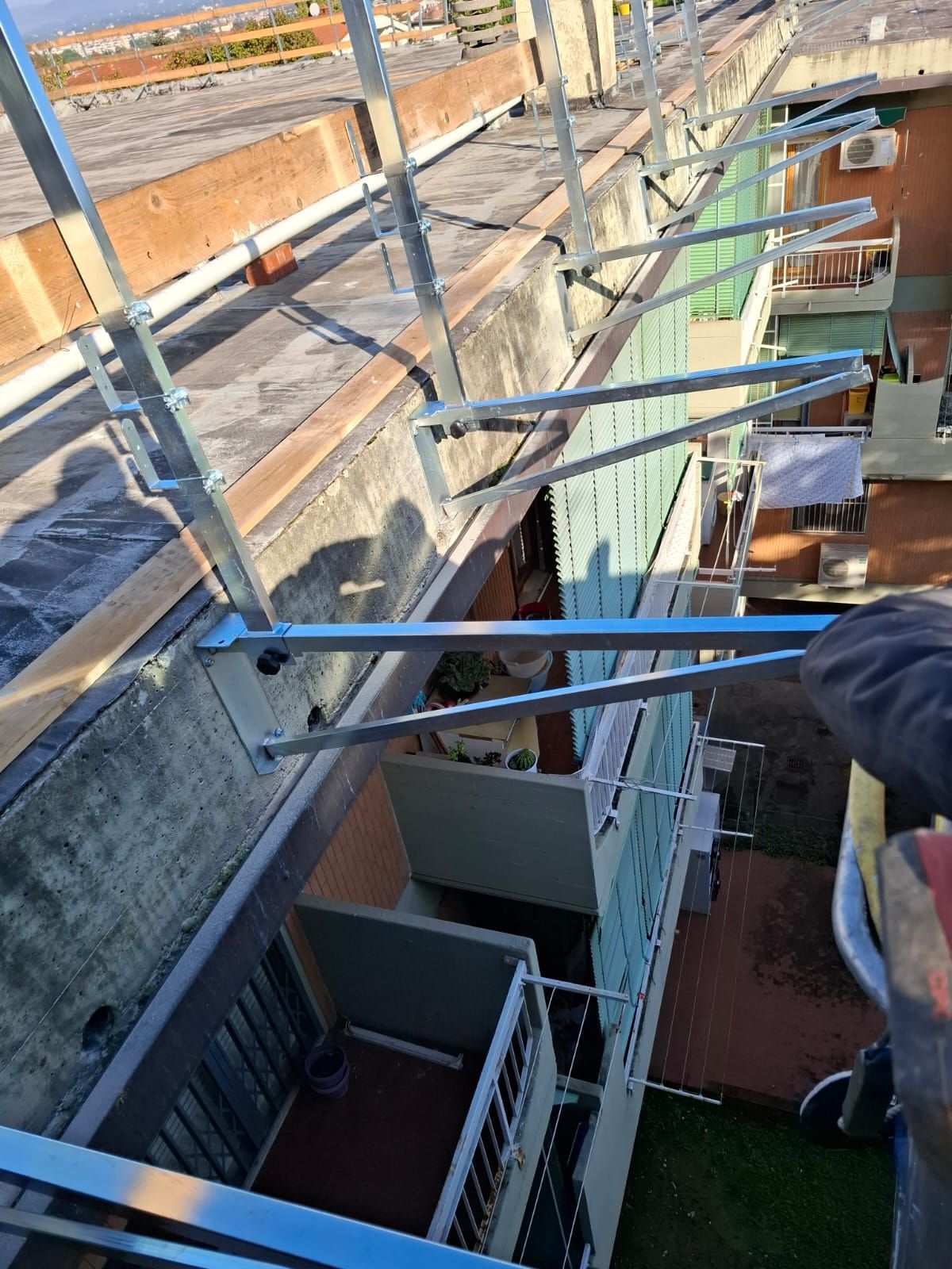 Una persona usa un lungo palo per raggiungere un punto al di sopra di uno stretto varco sul tetto di un edificio.