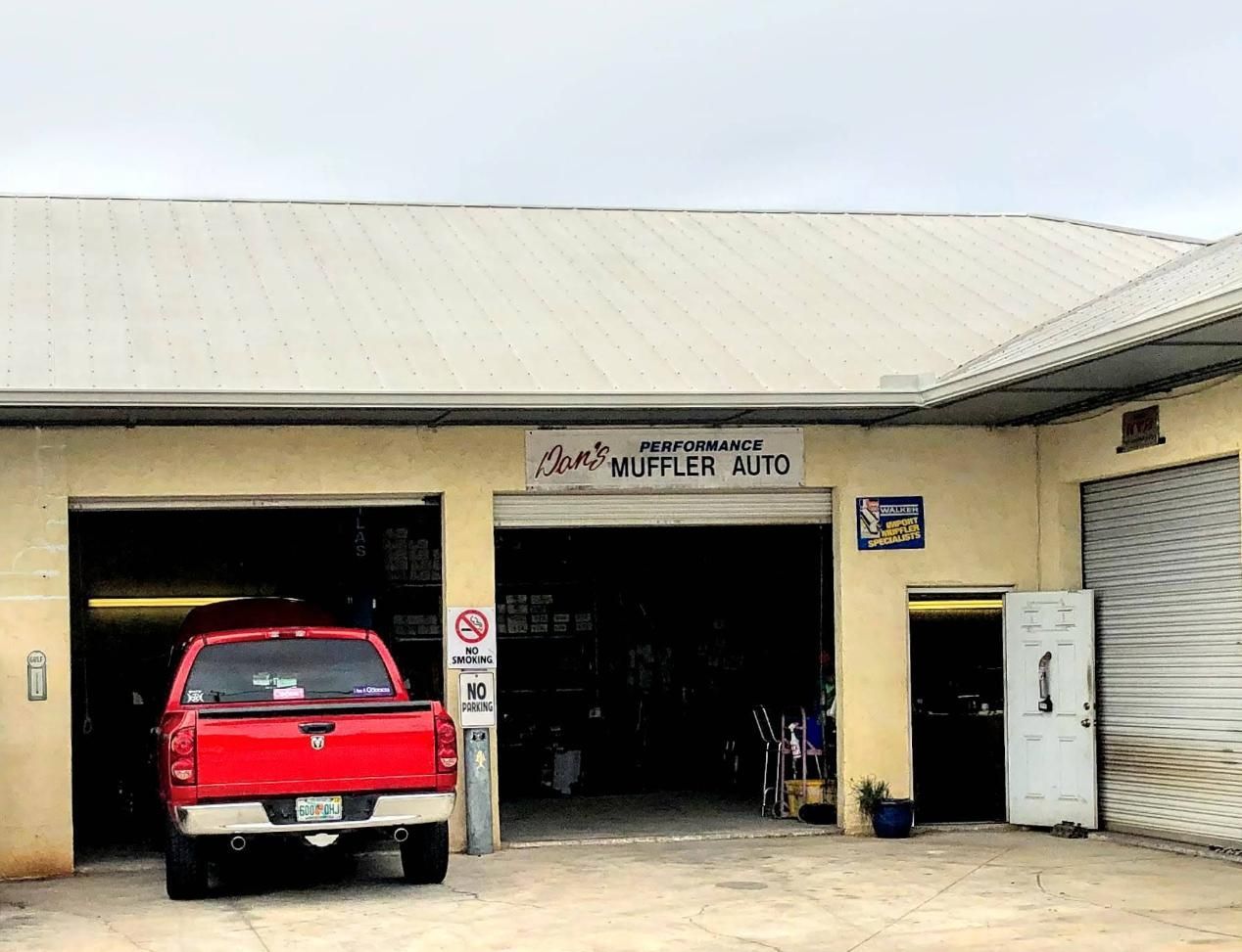 Red pickup truck parked in front of an open auto repair garage.