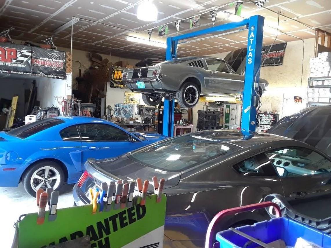 Auto repair shop with three cars, including a blue coupe, a black car, and a vehicle on a lift.