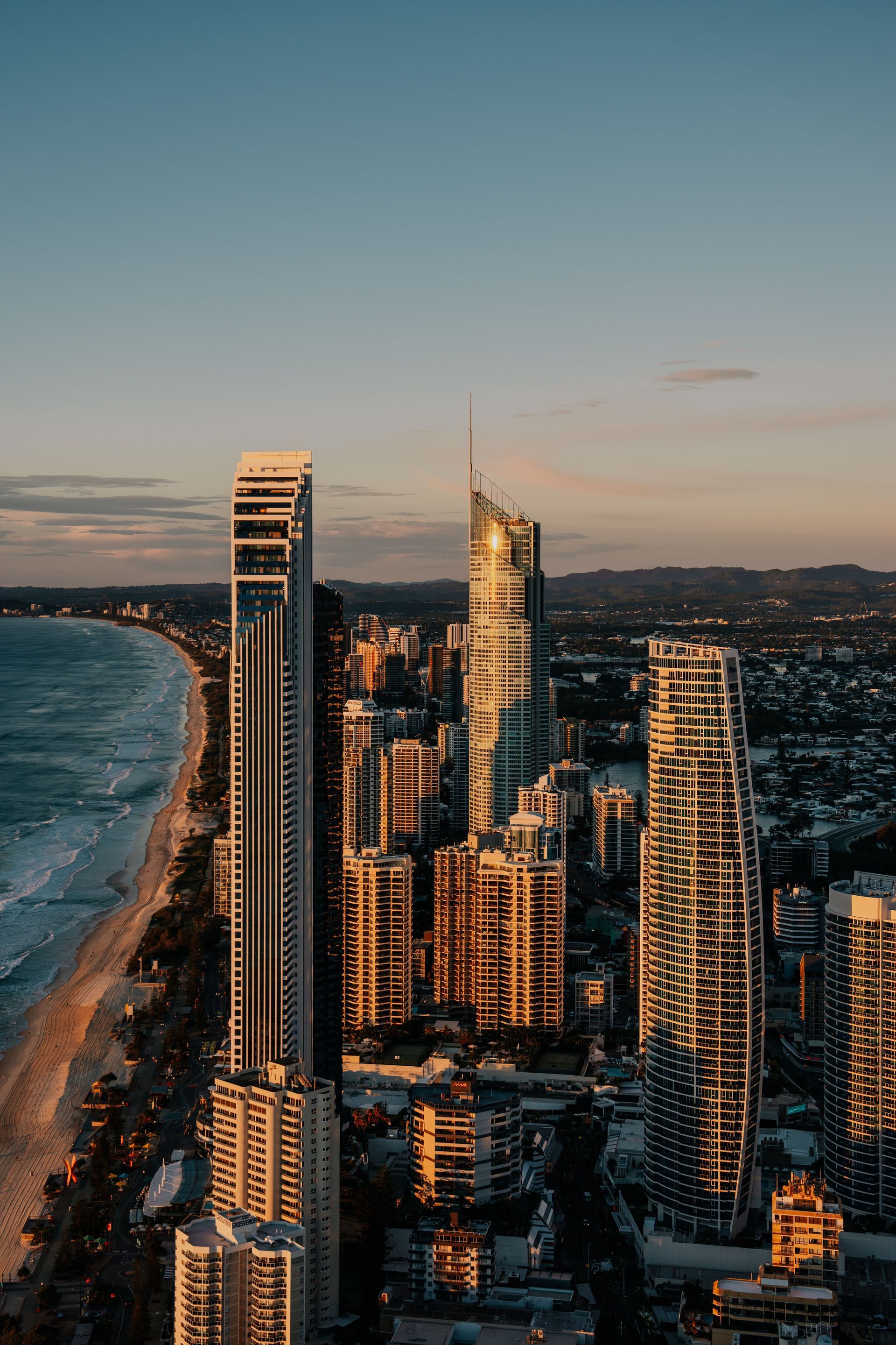 Sunset aerial view of coastal skyscrapers beside a beach and ocean